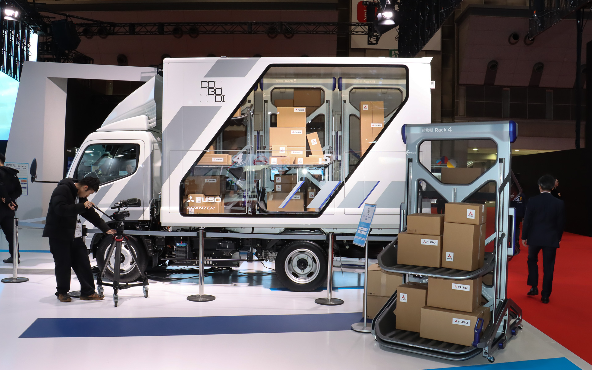 ソリューションの軸となるのは上下にスライドする3つの荷台テーブルを備えるカートリッジ式の専用台車。物流倉庫のトラックバースから荷物ごとトラックの荷台に搭載する