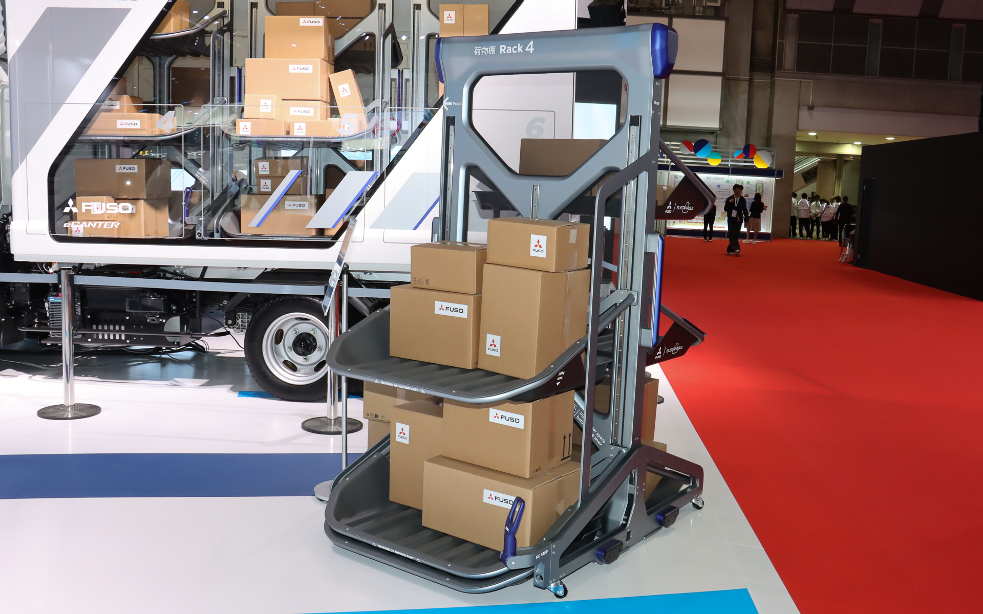 ソリューションの軸となるのは上下にスライドする3つの荷台テーブルを備えるカートリッジ式の専用台車。物流倉庫のトラックバースから荷物ごとトラックの荷台に搭載する