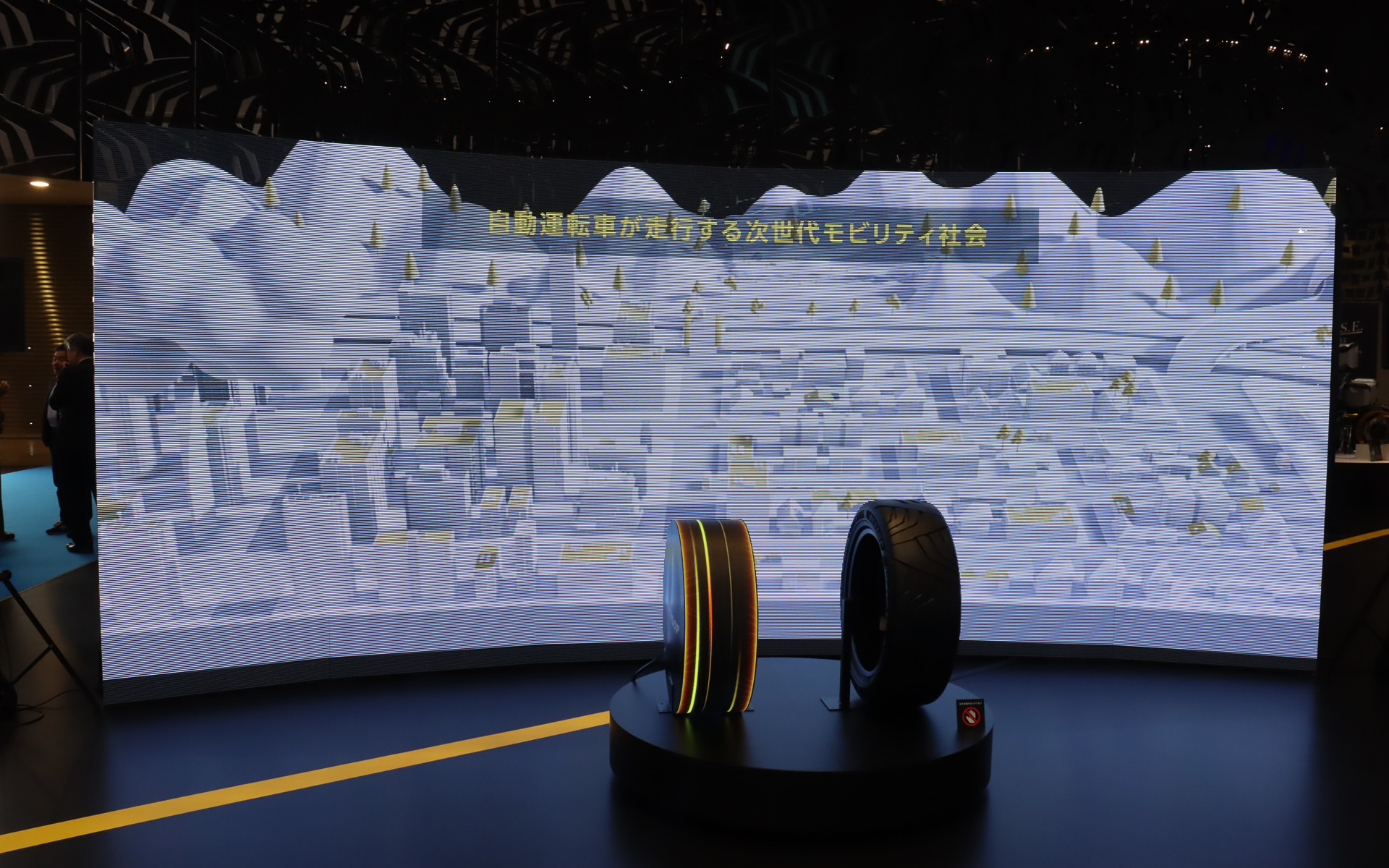 左側に置かれたタイヤ型のディスプレイで、タイヤの特性や形状を事前に最適化させるイメージを表現している