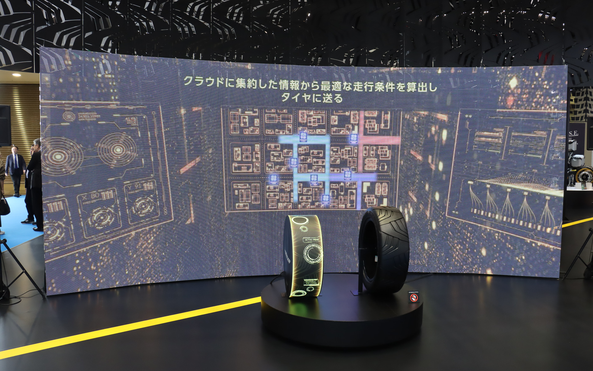 左側に置かれたタイヤ型のディスプレイで、タイヤの特性や形状を事前に最適化させるイメージを表現している