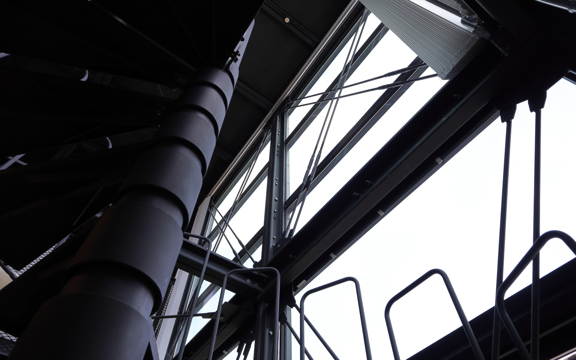 1階部分のリビング。一見して一般住宅のようだが壁際のダブルの筋違い、リズム感ある鉄鋼トラス梁、オリジナル鉄骨製のらせん階段などがあり、一般的な建売住宅とは明確に異なる作り込みがなされている