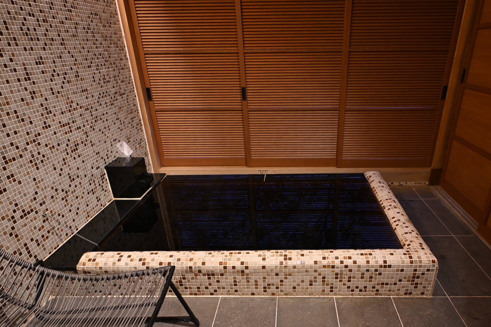 暖炉が備わる部屋に備え付けの内湯は美肌の湯として知られる希少な黒湯の天然温泉だ