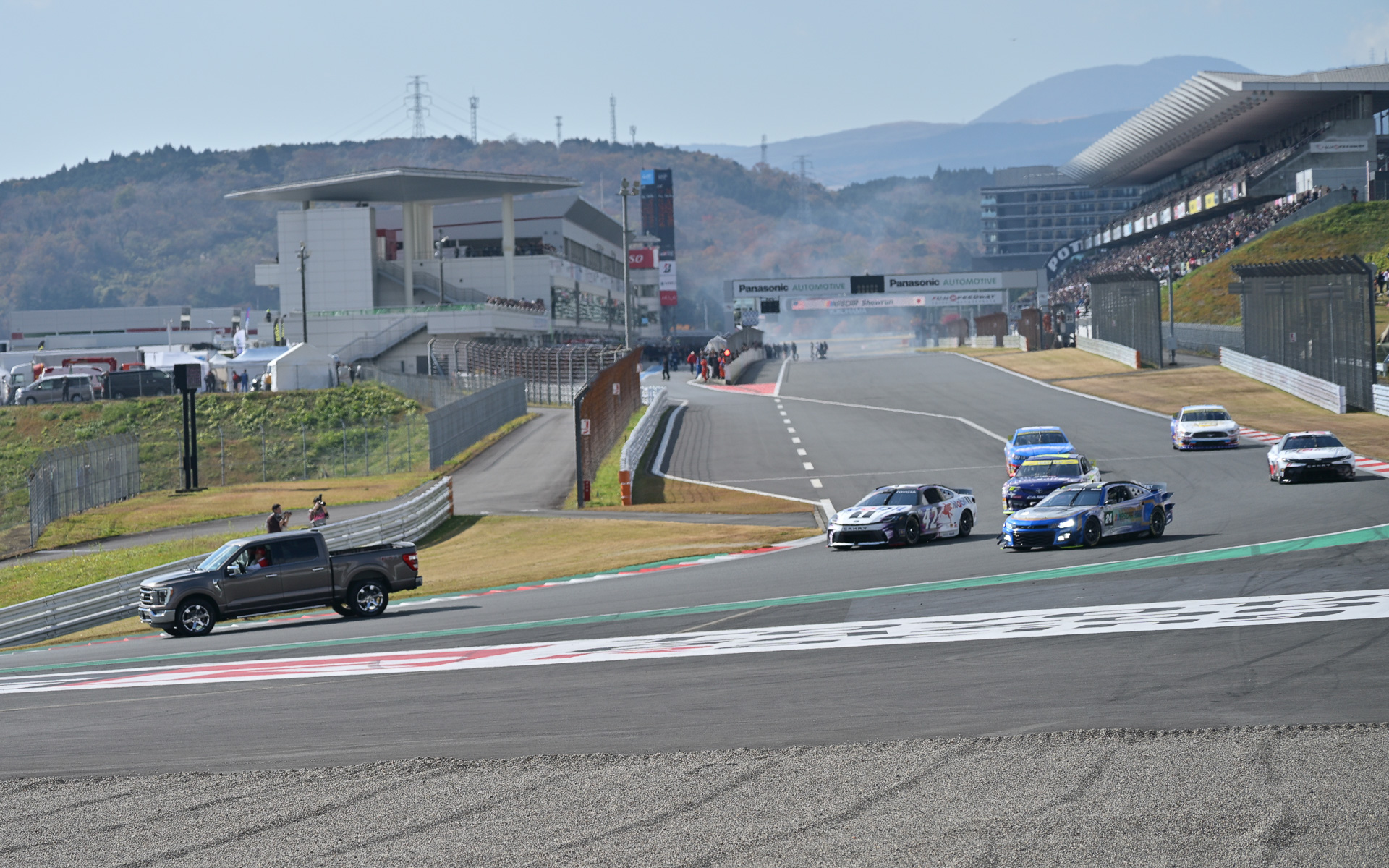 富士スピードウェイを走行するNASCAR。先導車はモリゾウ選手こと豊田章男会長の運転するフォード F-150。助手席にはジョージ・グラス駐日米国大使