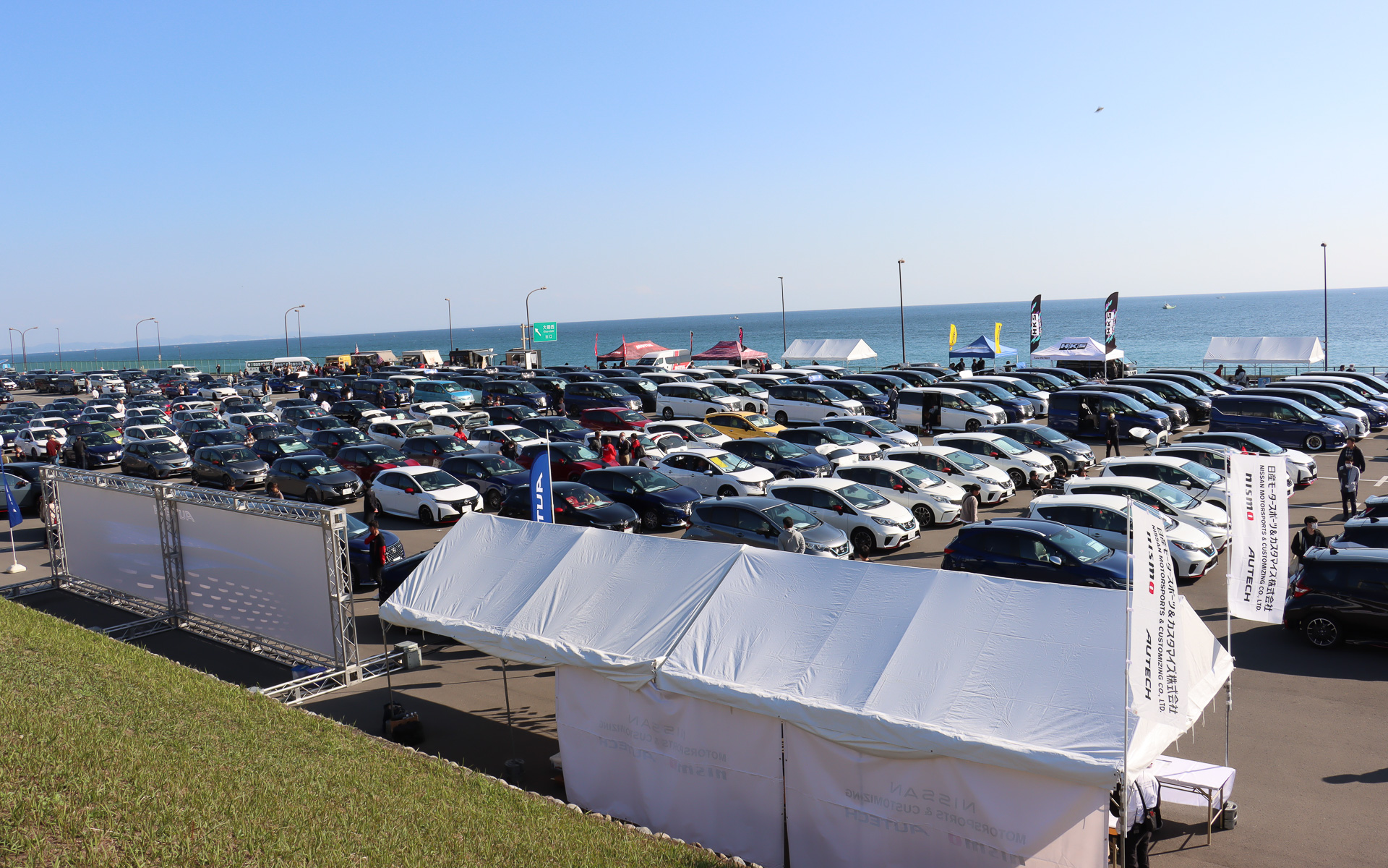 会場となった大磯ロングビーチ 第1駐車場では、中央のロッカーハウスを挟んで出入り口に近い東側に参加台数の多い「ノート＆ノート オーラ」「セレナ」「ミニバン」などが集まって駐車