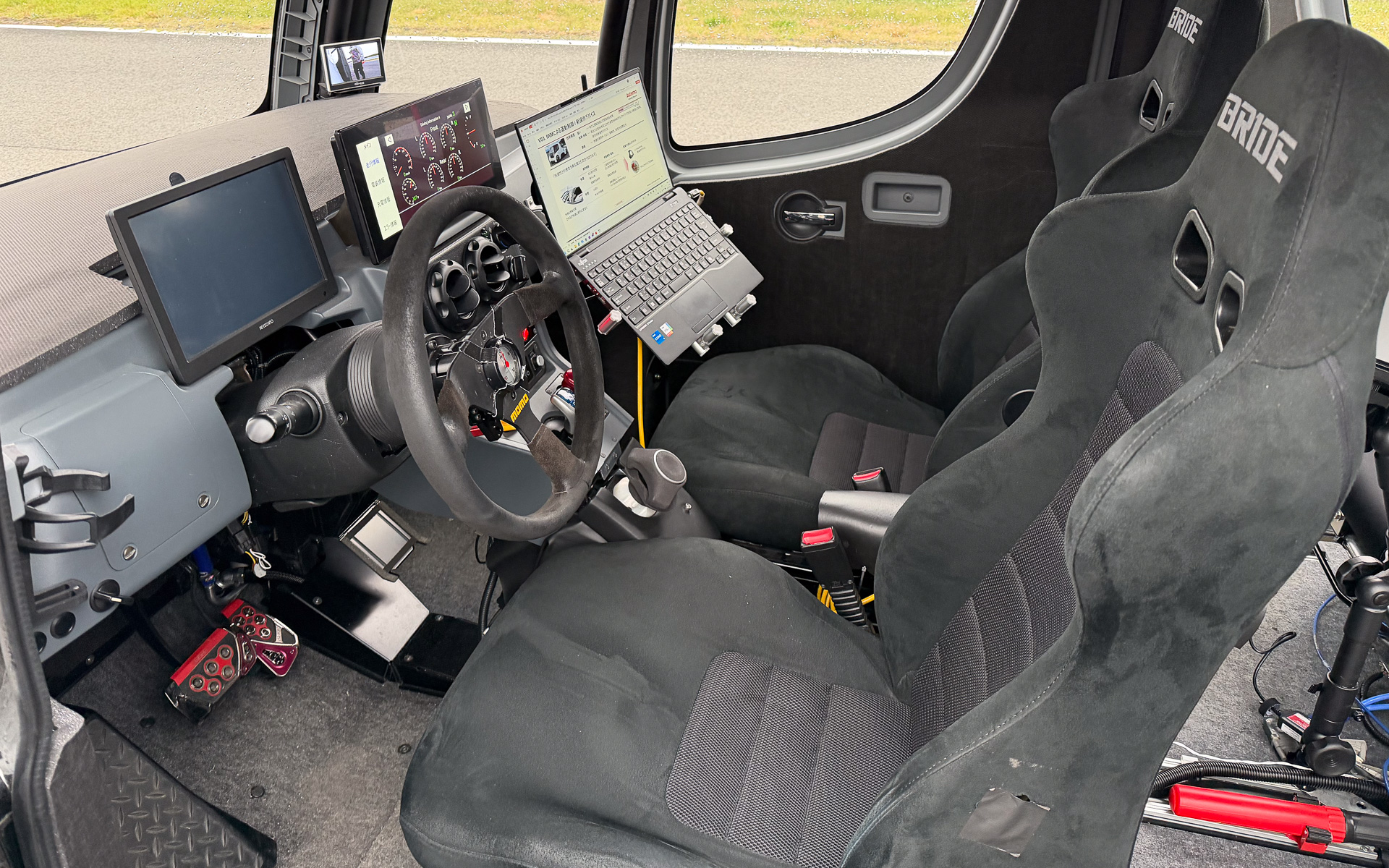 インホイールモーター開発車両のコクピット。室内空間が広いことをうたうインホイールモーターだが、なぜか室内はスパルタンな仕様。それはそれでかっこよいのだが……