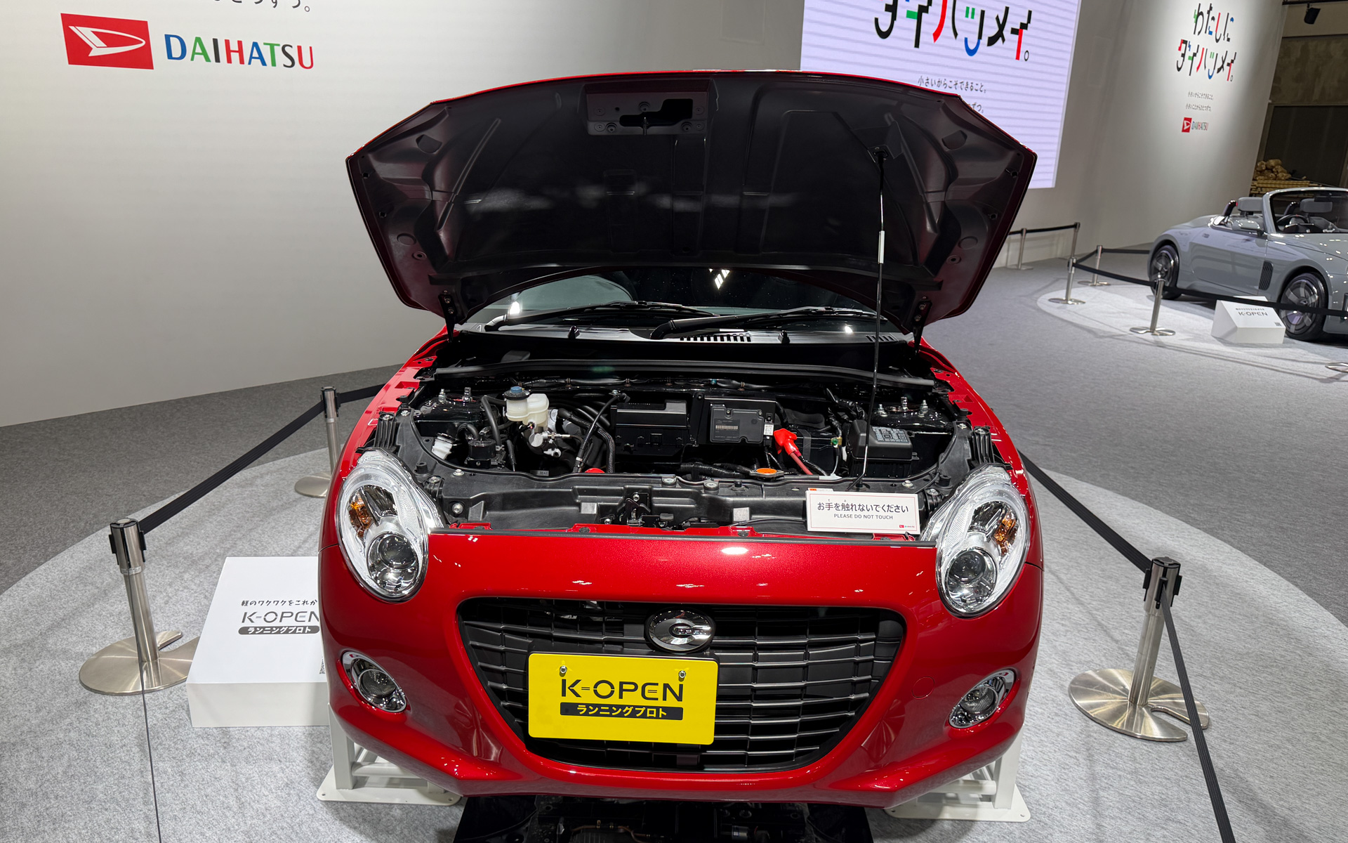 展示車両の「K-OPENランニングプロト」。ボンネットが開いた状態で展示されている