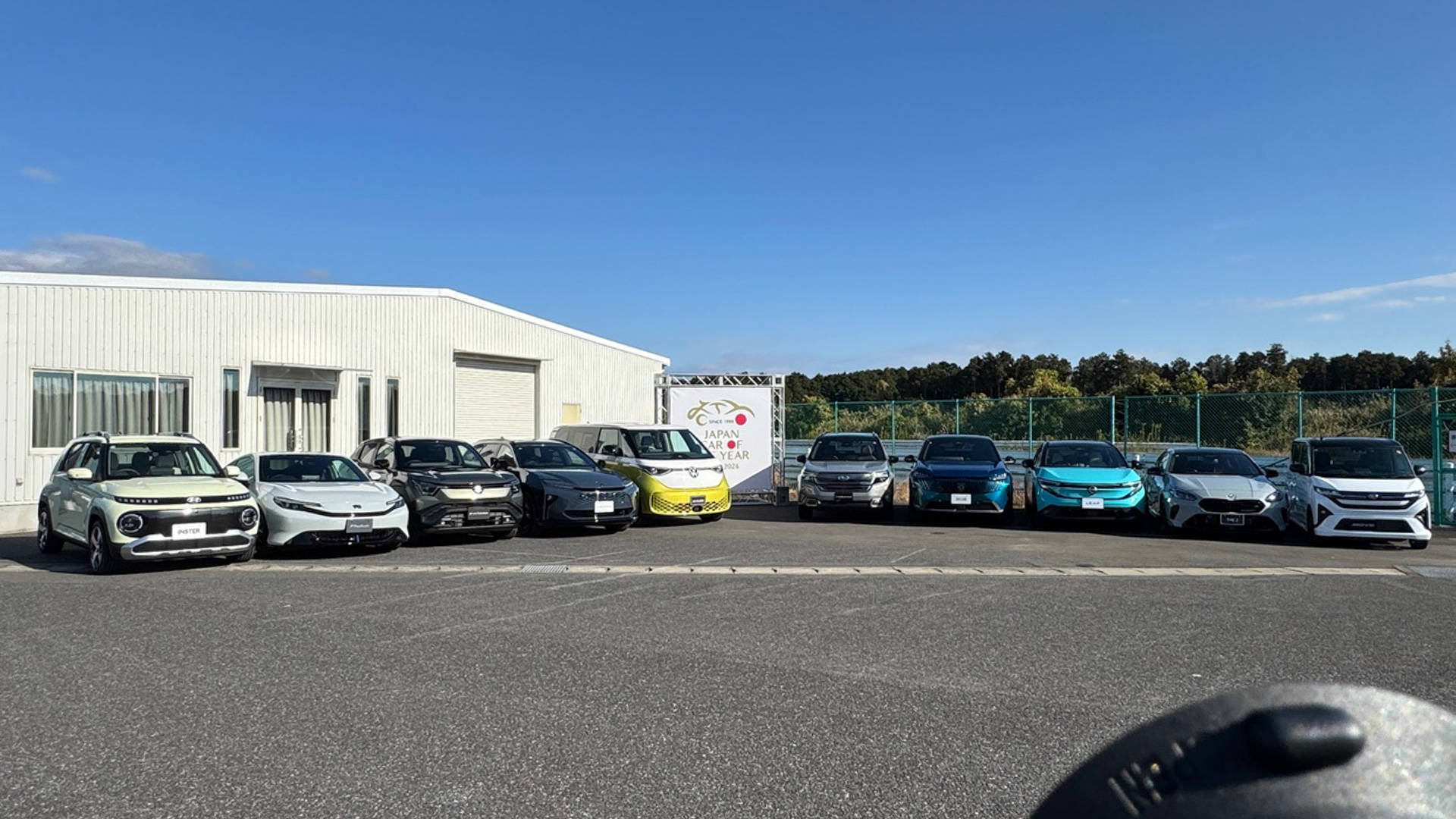 2025-2026 日本カー・オブ・ザ・イヤーの10ベストカーが、袖ヶ浦フォレストレースウェイに大集合。左からヒョンデ「インスター」、ホンダ「プレリュード」、スズキ「eビターラ」、トヨタ「クラウン（エステート）」、フォルクスワーゲン「ID.Buzz」、スバル「フォレスター」、プジョー「3008」、日産「リーフ」、BMW「2シリーズグランクーペ」、ダイハツ「ムーヴ」の10台です