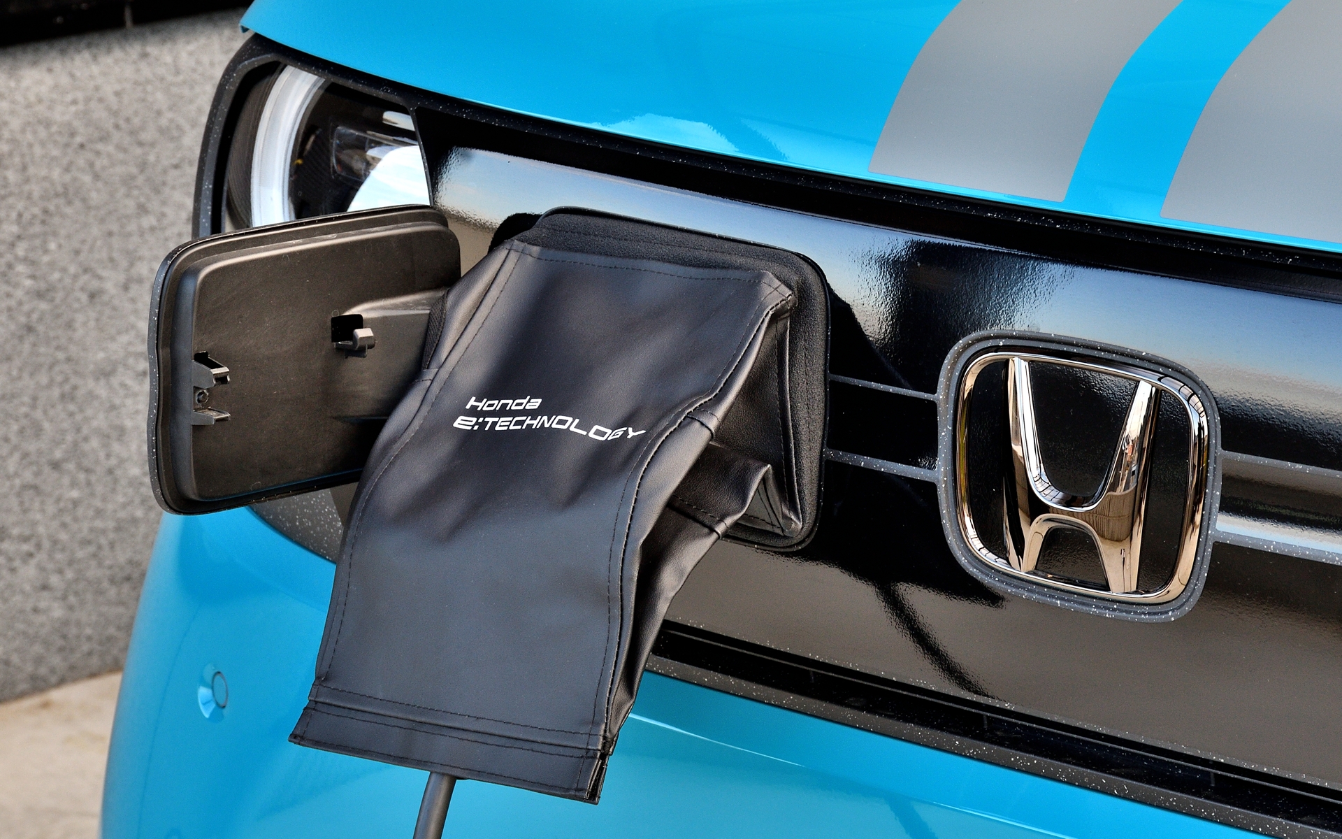 N-ONE e:の普通充電ポートは正面向かって左側に配置されている。また純正アクセサリーには、屋外での充電の際、充電ポート内や充電コネクターを「ほこり・汚れ・雨」から保護してくれるほか、紫外線の低減にも役立つ「ポートリッドカバー」もラインアップされている。価格は収納袋付きで1万6500円