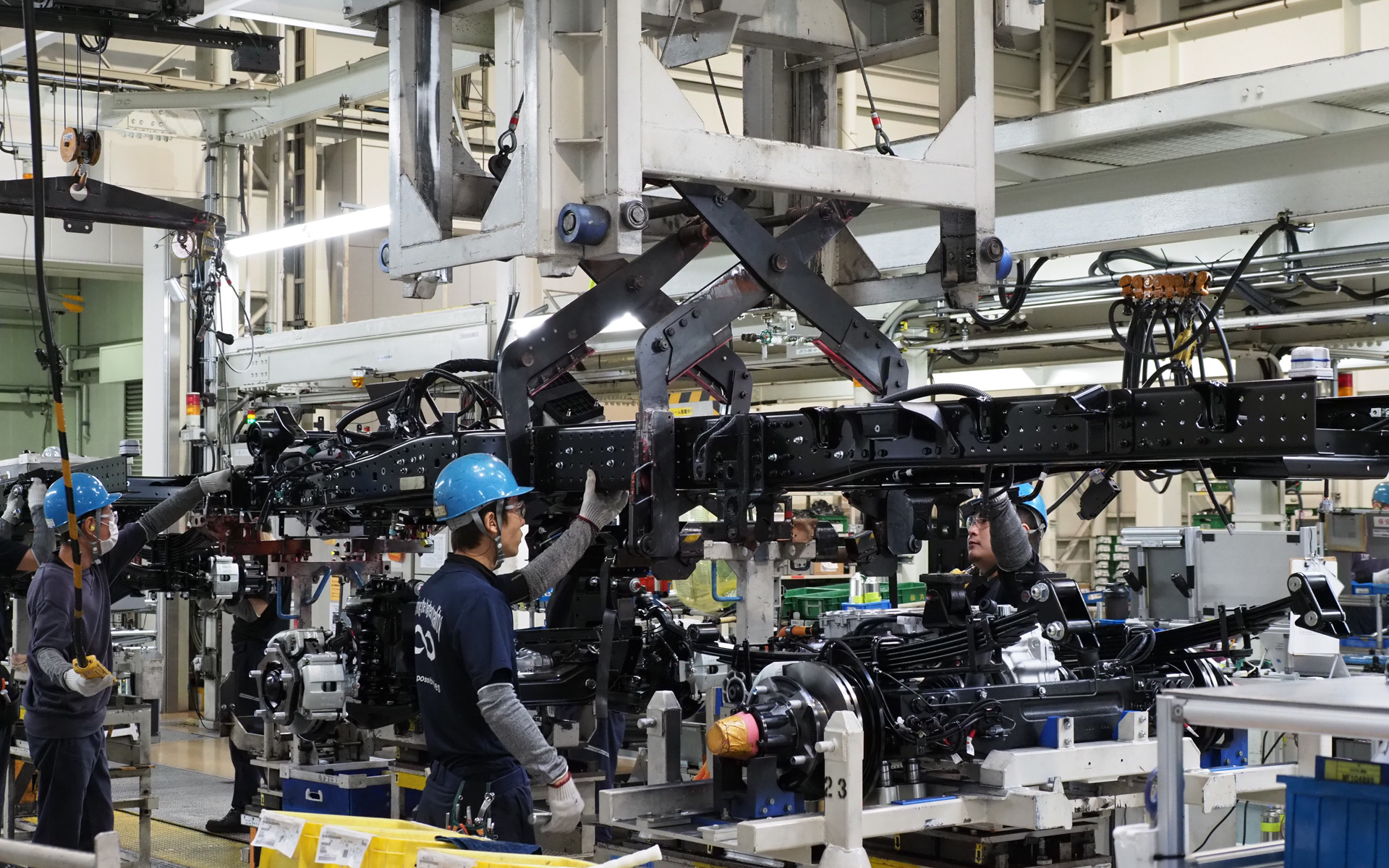 フレームにリアのeアクスルを含むフロントアクスルを組み付ける。これはディーゼルのキャンターのアクスル組み付けと同じ（工場内は撮影は許可されないためラインの写真は三菱ふそう提供）