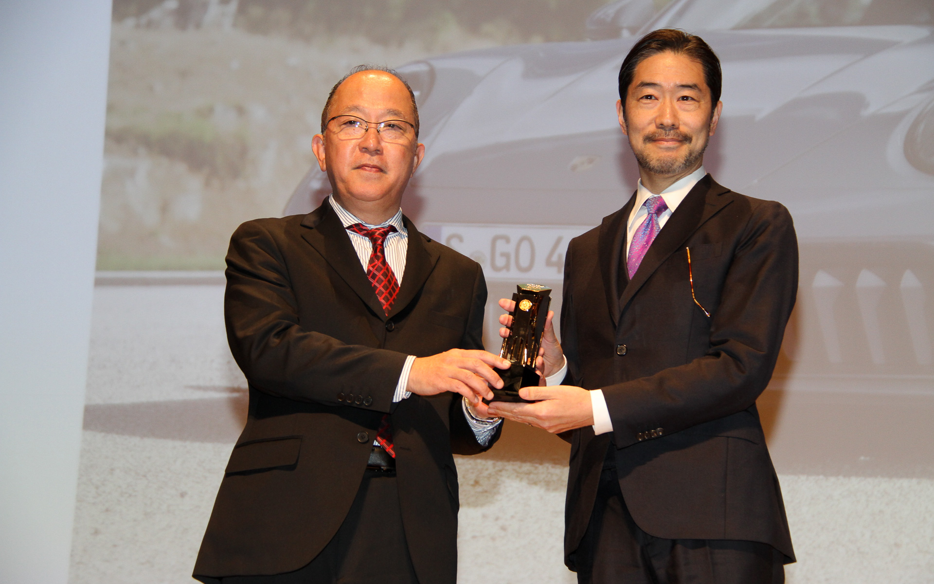 2025-2026 テクノロジー・カー・オブ・ザ・イヤーに選ばれた「ポルシェ 911 カレラ GTS」。ポルシェジャパン株式会社 広報部長 黒岩真治氏は「2025年、ポルシェジャパンはフル電動マカンを国内にローンチしました。駆動方式を増やす中で、電動モーターを市販の911に初めて採用し、そして新開発のハイブリッドシステム『T-ハイブリッド』を搭載した911 カレラGTSを国内に導入しました。このハイブリッドシステムは効率を高めるだけでなく、ポルシェが持つポルシェらしいドライビングプレジャーやパフォーマンスを高めるといった性能の向上に特化した点を評価いただいたと思っております。イモー・ブッシュマンからありました通り、今年はポルシェジャパン創立30周年の年です。このような年にポルシェとして46回の歴史を誇る日本カー・オブ・ザ・イヤーで初めてポルシェが賞をいただき、会社として大変光栄なことと存じます。30年前にインポーターで仕事を始めまして、以来、合計10の自動車ブランドの広報に携わり、そして今日、ポルシェでカー・オブ・ザ・イヤーの賞を2つ同時にいただくという、人生で最高の夢をいただいた瞬間です」と述べた