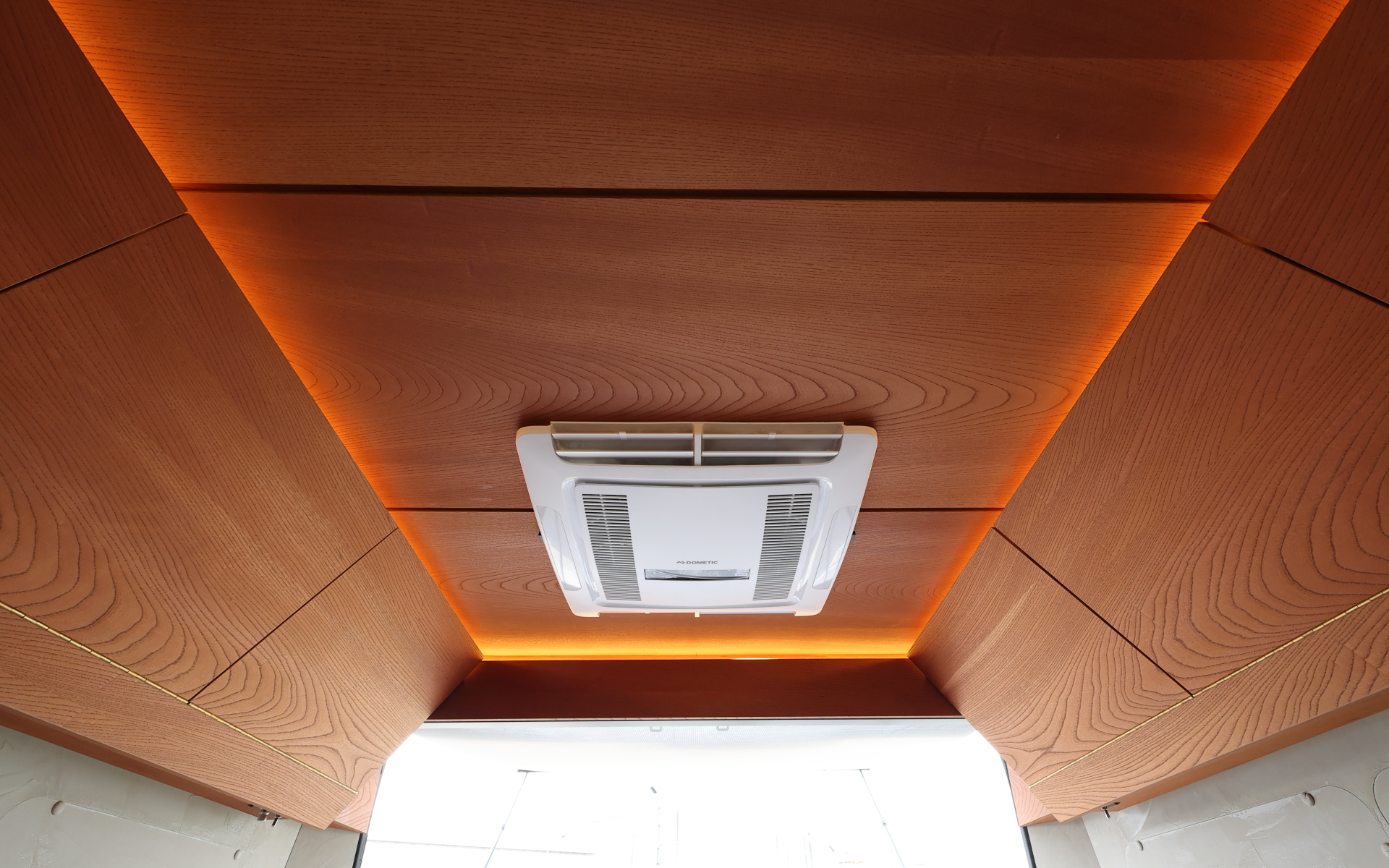 インテリアではブリッドと共同開発したキャンピングカー専用のバケットシートを運転席&助手席にセット。また“移動する別荘”を目指し、天然素材のケヤキの木目を生かしたデザインで上質感を演出する吊り戸棚、対面式のベンチソファー、ベンチソファーと組み合わせることで簡単にセットアップできるベッド(1800×1800mm)、大型のリアオープンデッキ、電子レンジと85Lの冷蔵庫を1か所にレイアウトしたキッチン、外部電源による充電と走行充電で電力を確保できるサブバッテリ(リン酸鉄リチウムイオン/5kWh)などを装備。タープやサンシェードなども付属する