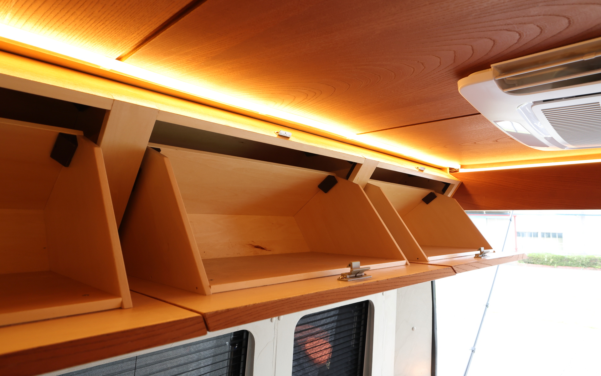 インテリアではブリッドと共同開発したキャンピングカー専用のバケットシートを運転席&助手席にセット。また“移動する別荘”を目指し、天然素材のケヤキの木目を生かしたデザインで上質感を演出する吊り戸棚、対面式のベンチソファー、ベンチソファーと組み合わせることで簡単にセットアップできるベッド(1800×1800mm)、大型のリアオープンデッキ、電子レンジと85Lの冷蔵庫を1か所にレイアウトしたキッチン、外部電源による充電と走行充電で電力を確保できるサブバッテリ(リン酸鉄リチウムイオン/5kWh)などを装備。タープやサンシェードなども付属する