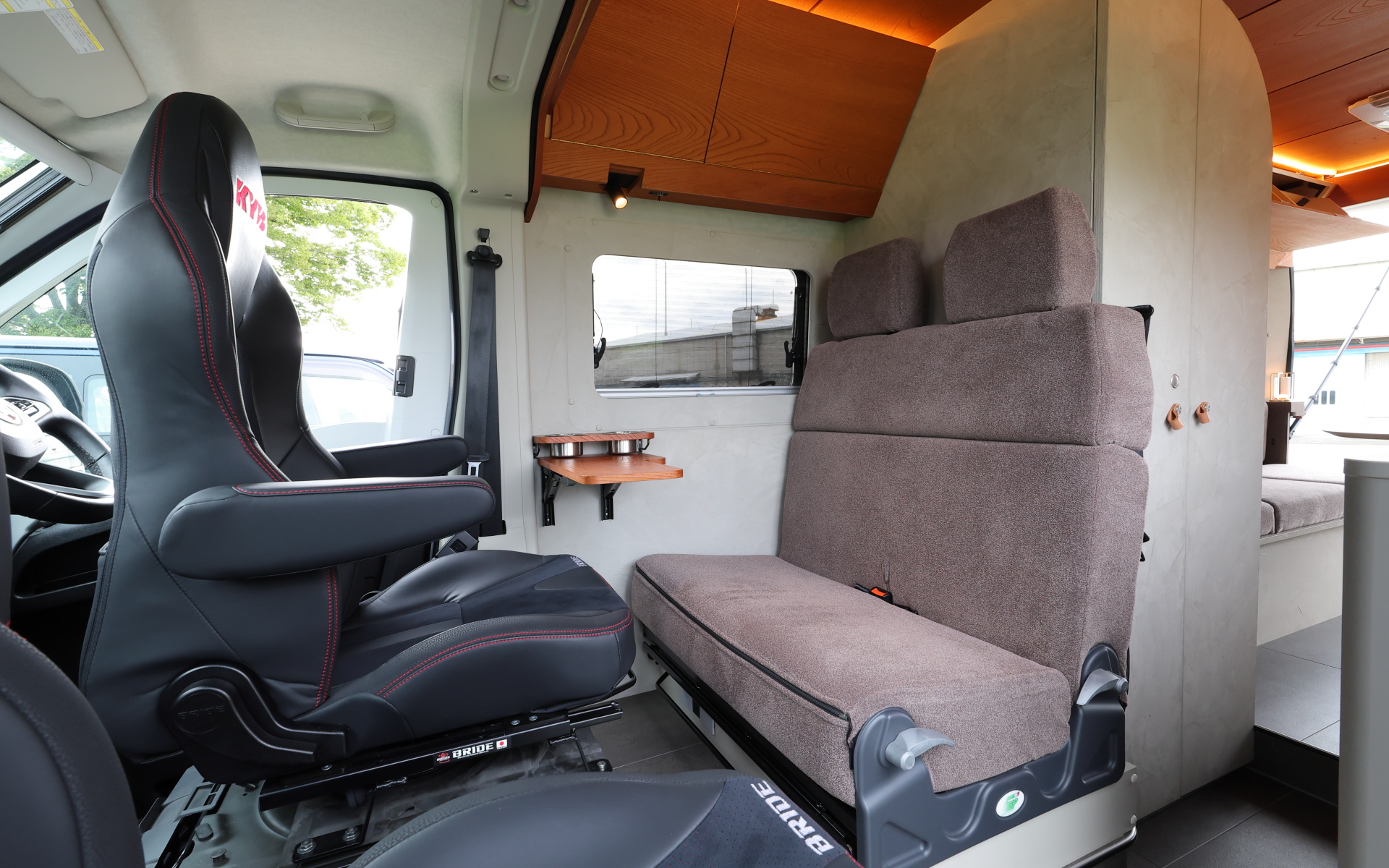 インテリアではブリッドと共同開発したキャンピングカー専用のバケットシートを運転席＆助手席にセット。また“移動する別荘”を目指し、天然素材のケヤキの木目を生かしたデザインで上質感を演出する吊り戸棚、対面式のベンチソファー、ベンチソファーと組み合わせることで簡単にセットアップできるベッド（1800×1800mm）、大型のリアオープンデッキ、電子レンジと85Lの冷蔵庫を1か所にレイアウトしたキッチン、外部電源による充電と走行充電で電力を確保できるサブバッテリ（リン酸鉄リチウムイオン/5kWh）などを装備。タープやサンシェードなども付属する
