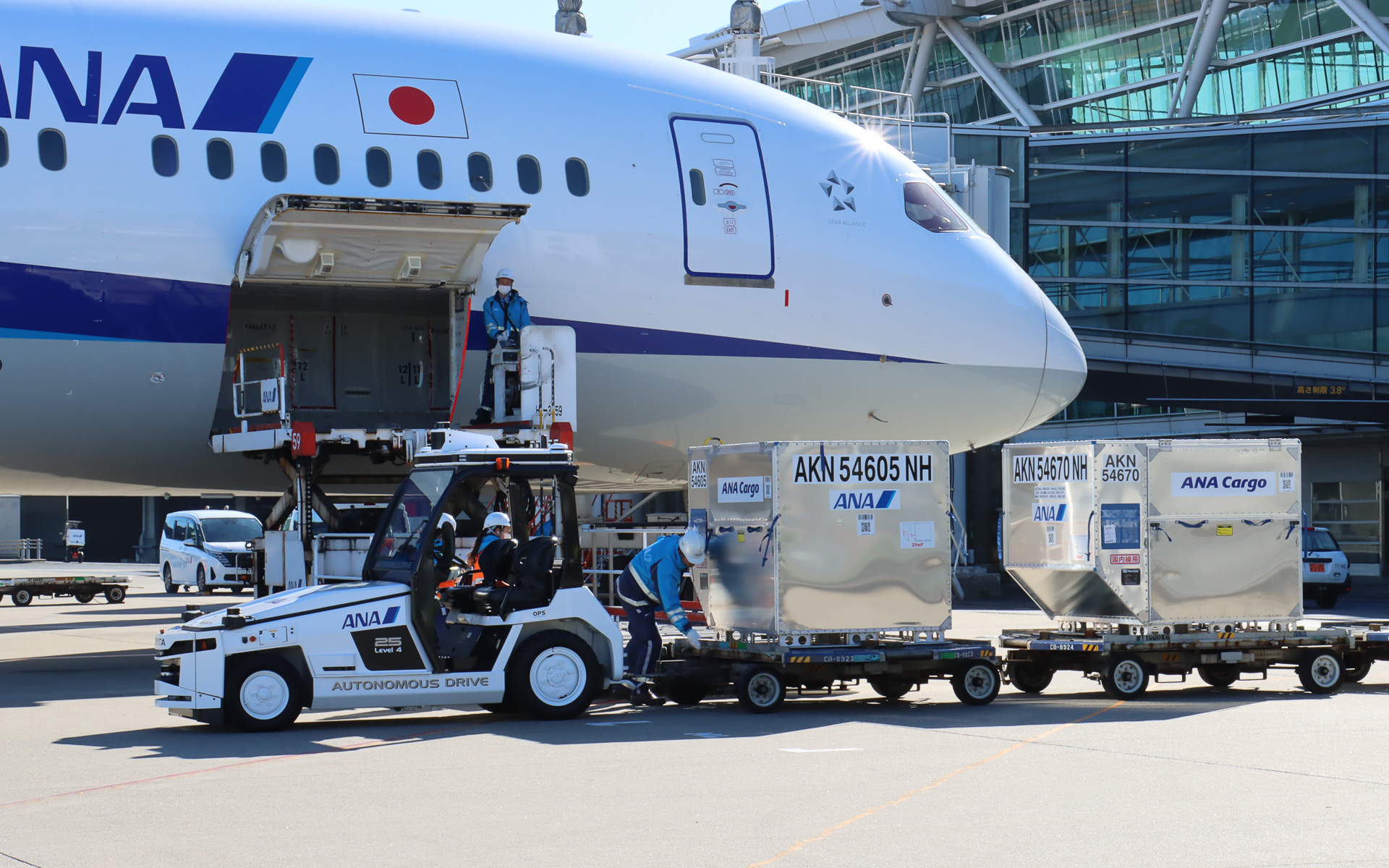 スタッフが飛行機に隣接する位置まで手動運転し、貨物が手際よく降ろされていく