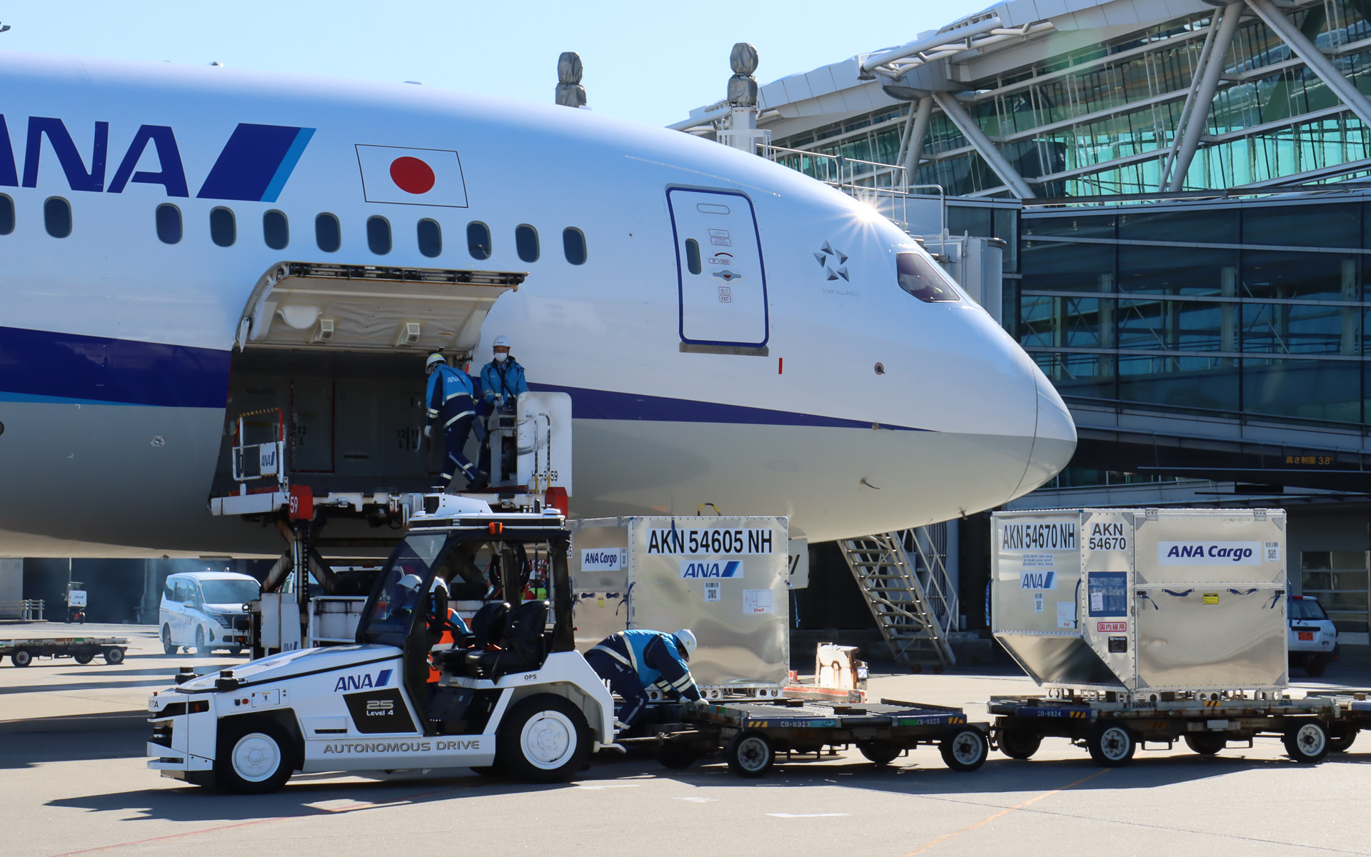 スタッフが飛行機に隣接する位置まで手動運転し、貨物が手際よく降ろされていく