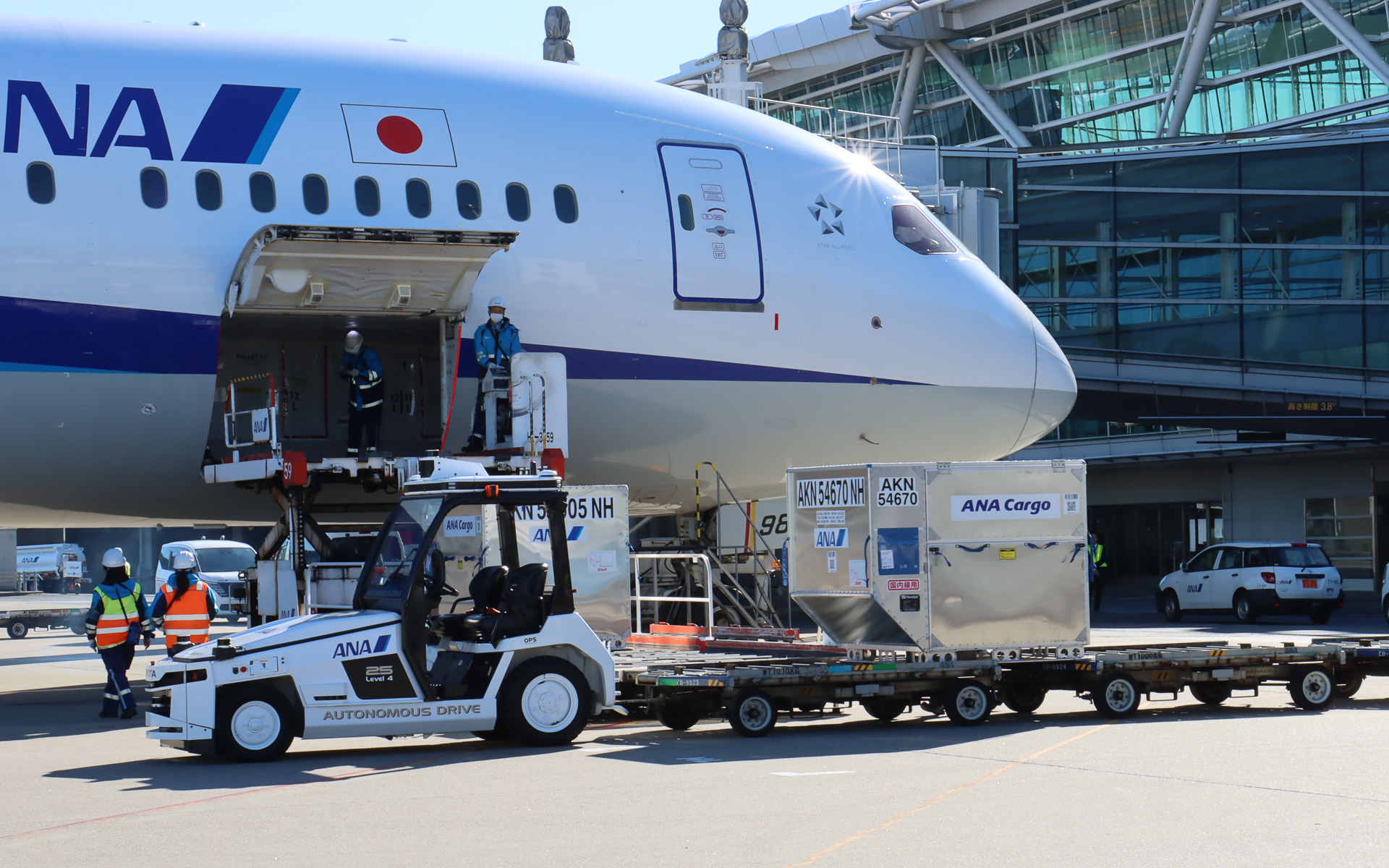 スタッフが飛行機に隣接する位置まで手動運転し、貨物が手際よく降ろされていく