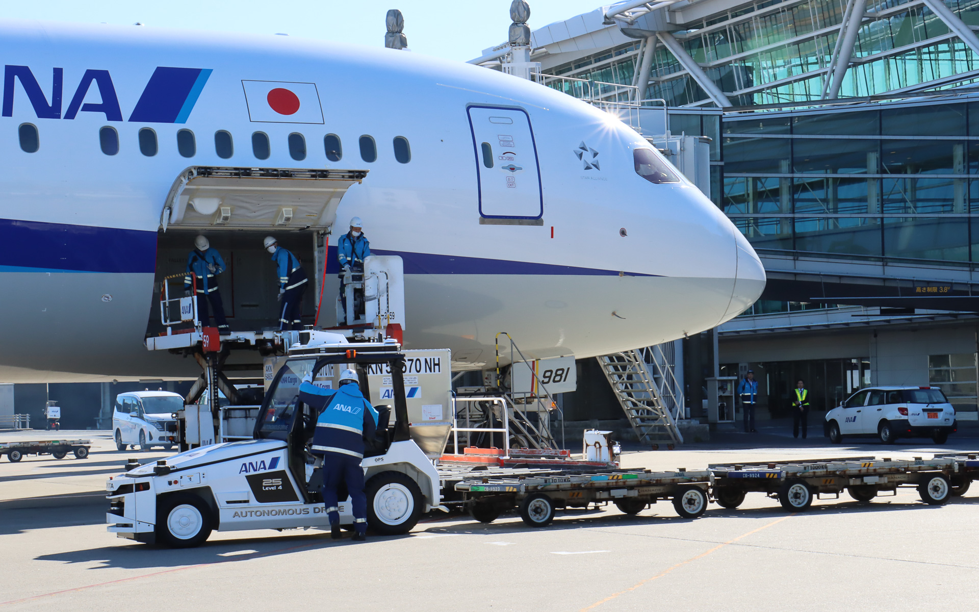 スタッフが飛行機に隣接する位置まで手動運転し、貨物が手際よく降ろされていく