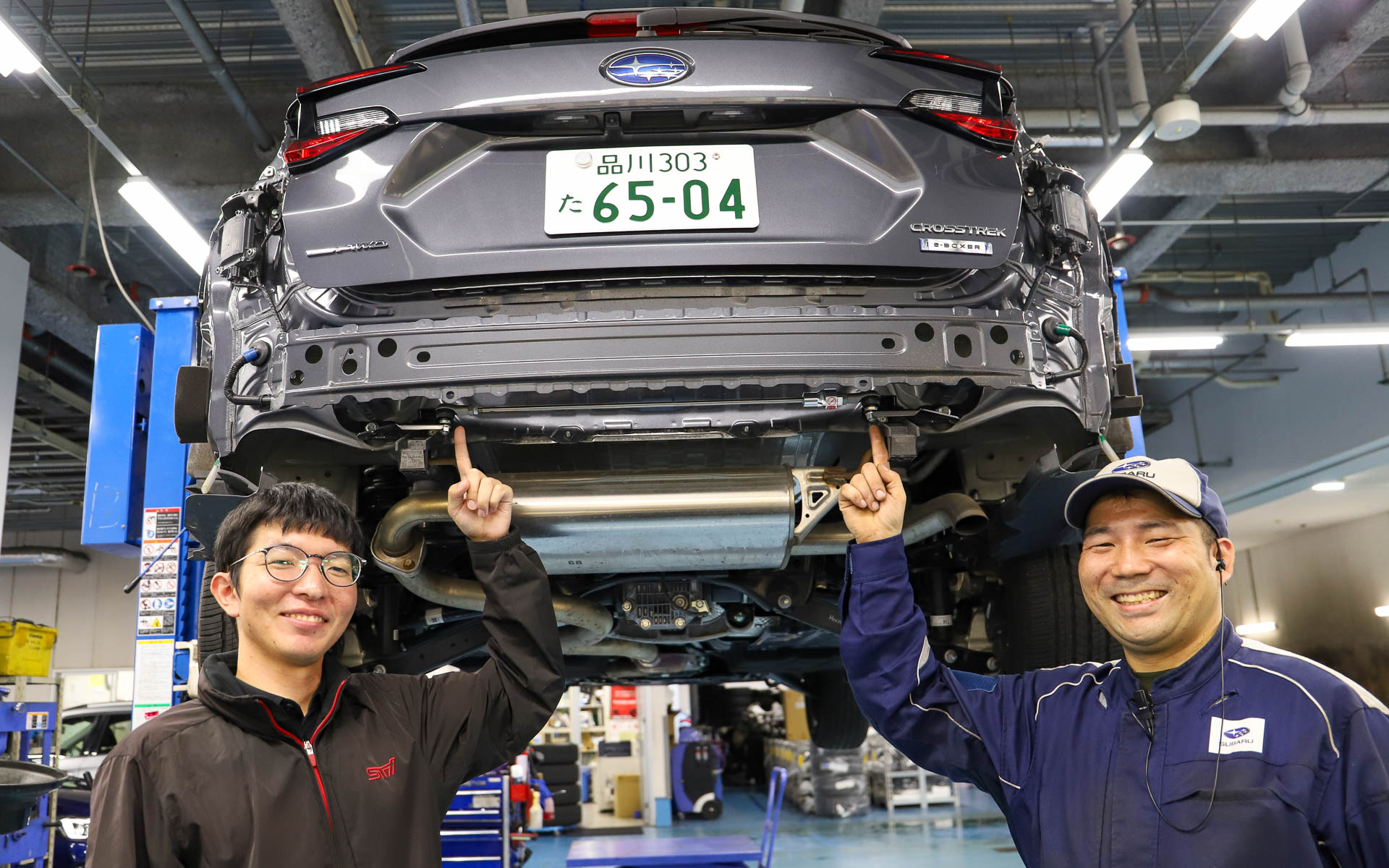 STIの柏井健太郎さん（左）に話を聞きながら、ニュルブルクリンク24時間レースに選抜メカニックとして参戦した経験もある東京スバル三鷹店の三上嵩メカニック（右）に「STIフレキシブルドロースティフナー リア」を取り付けてもらった