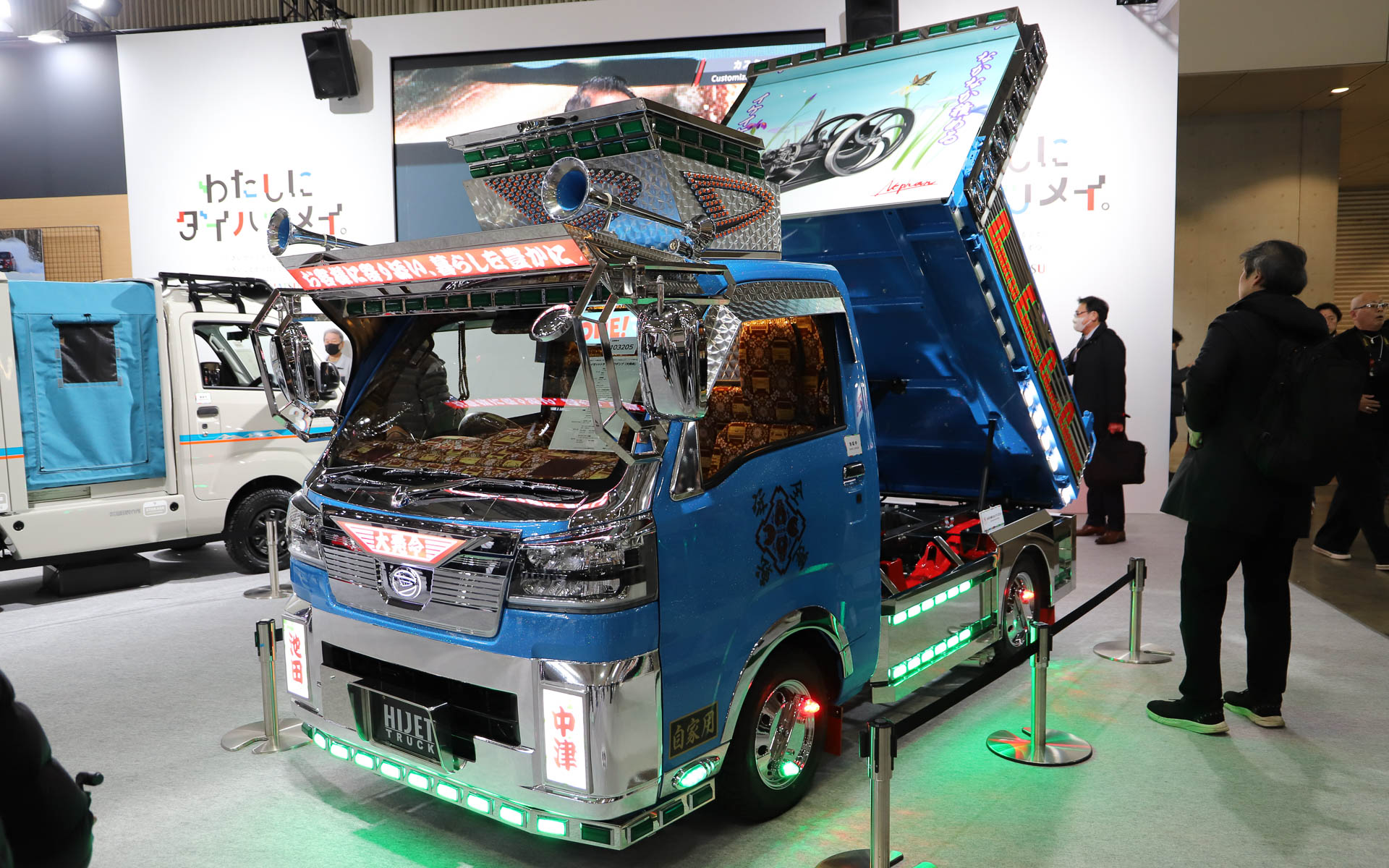 ハイゼット トラックのデコトラ「ハイゼット トラック PTO ダンプ 大発命（ダイハツメイ）」。リアのパネルには描き起こしの歴代ハイゼットが並び、オリジナルデザインのステアリングカバーで輪投げができるようになっている