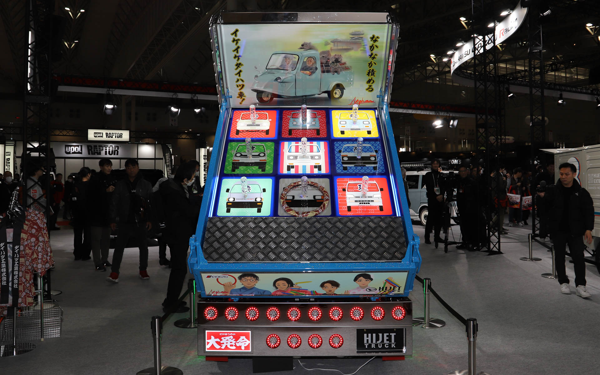 ハイゼット トラックのデコトラ「ハイゼット トラック PTO ダンプ 大発命（ダイハツメイ）」。リアのパネルには描き起こしの歴代ハイゼットが並び、オリジナルデザインのステアリングカバーで輪投げができるようになっている