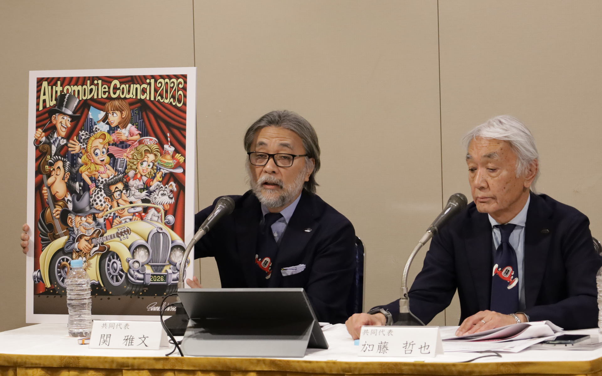 AUTOMOBILE COUNCIL 2026のメインビジュアルを公開するAUTOMOBILE COUNCIL実行委員会 共同代表の関雅文氏（左）と加藤哲也氏（右）