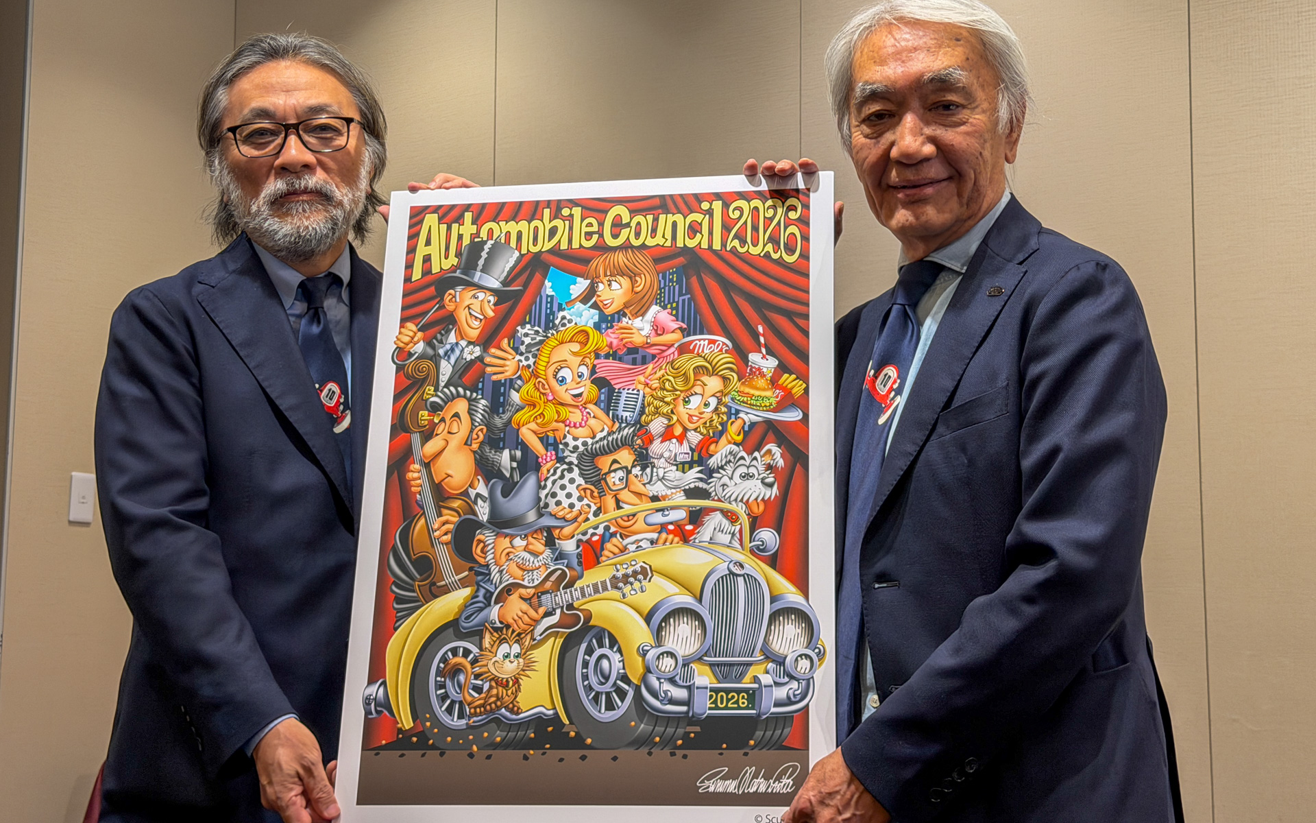 AUTOMOBILE COUNCIL 2026のメインビジュアルを掲げるAUTOMOBILE COUNCIL実行委員会 共同代表の関雅文氏（左）と加藤哲也氏（右）