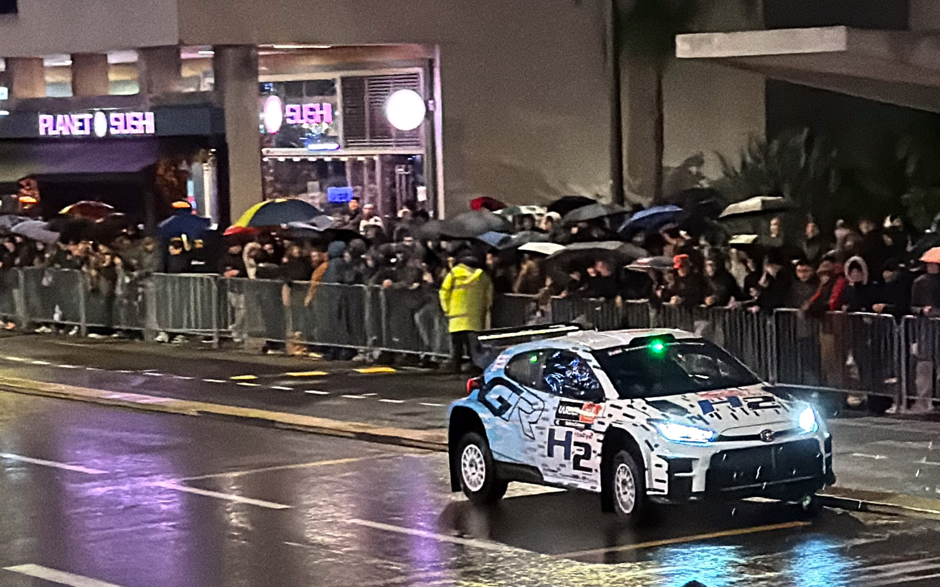雨の中、F1のスタート地点として有名なPLANET SUSHI前をデモランする水素ラリーカー「GRヤリス ラリー2 H2コンセプト」