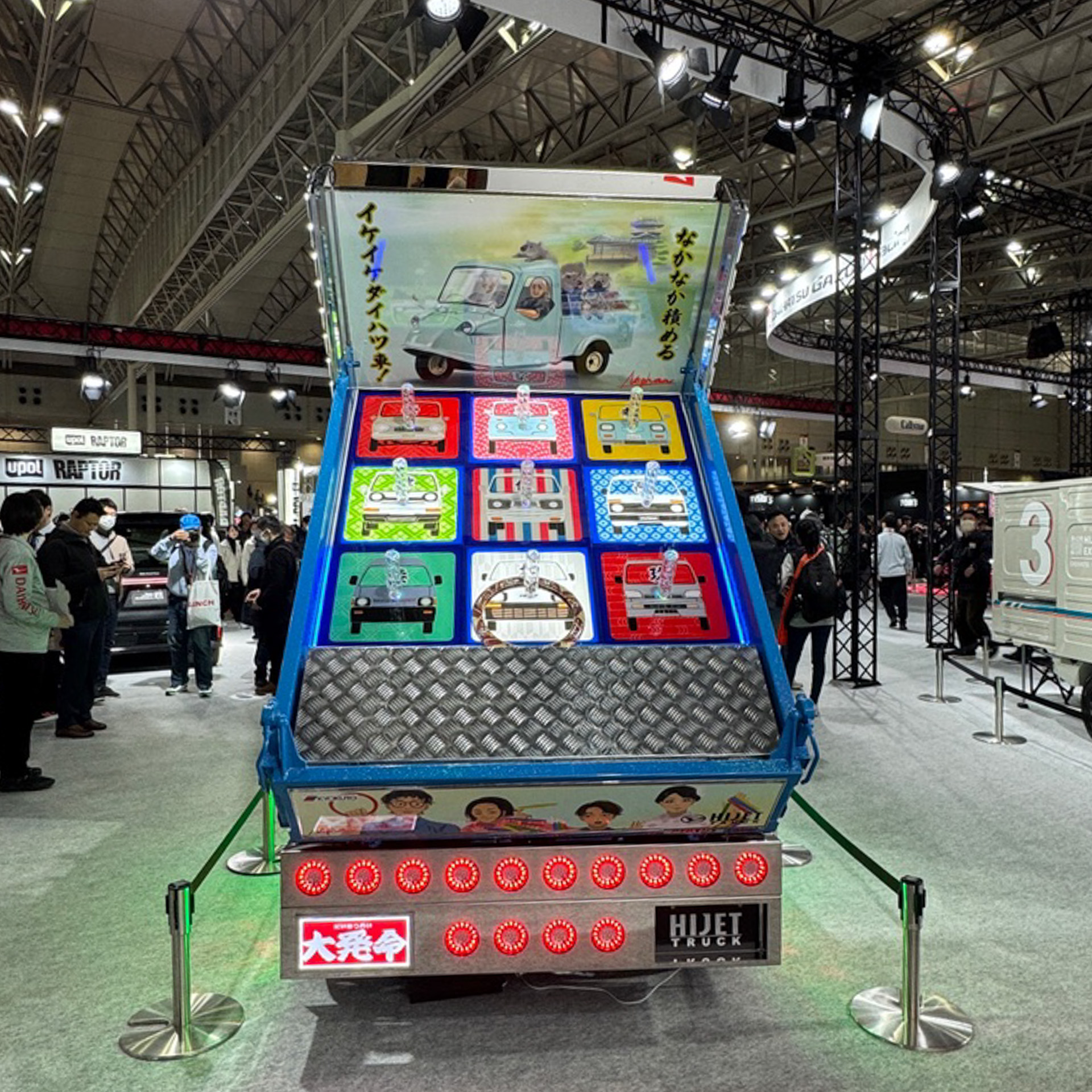 ダイハツのブースに展示されていたデコトラ仕様の「ハイゼット トラック PTO ダンプ 大発命（ダイハツメイ）」の積載部分は、なんと輪投げの的になっているんです。しかも、歴代ハイゼットをモチーフとしたイラストがいいですね