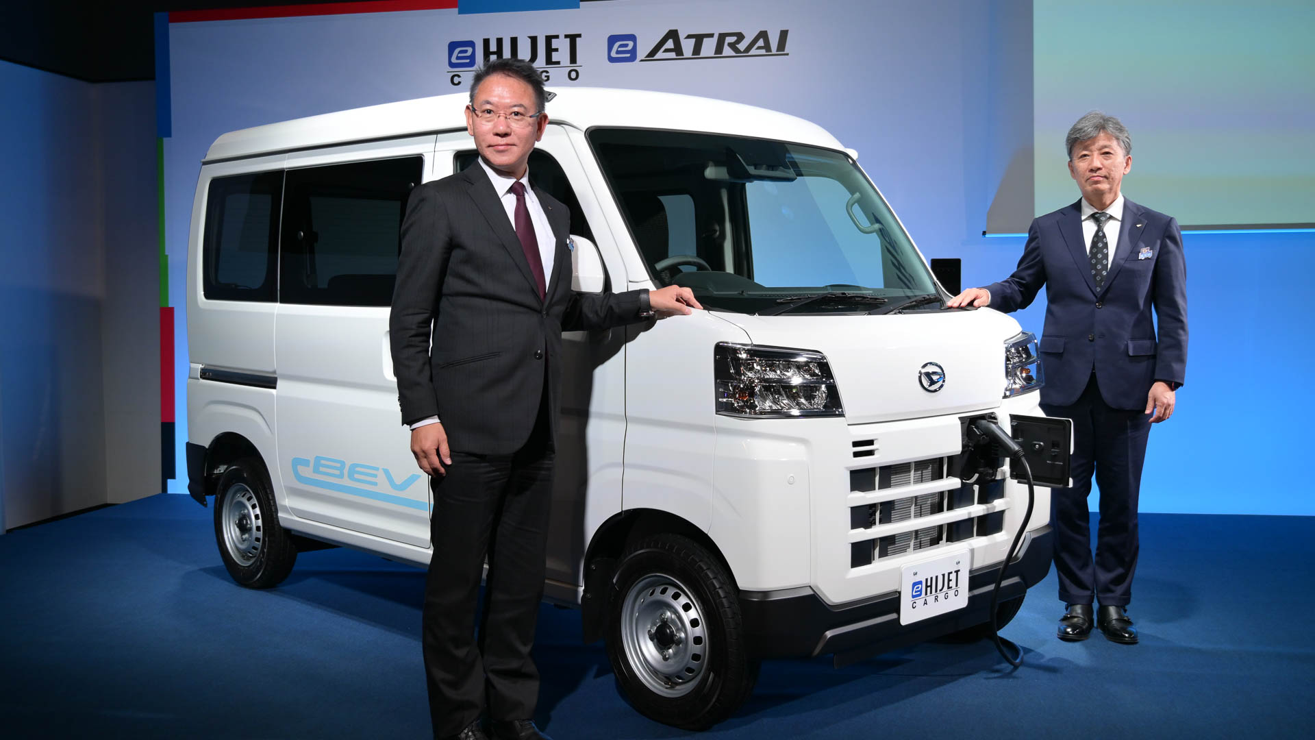 e-ハイゼット カーゴと、ダイハツ工業株式会社 製品企画部 主査/プロジェクト責任者 齋藤寛氏（左）、ダイハツ工業株式会社 取締役社長 井上雅宏氏（右）