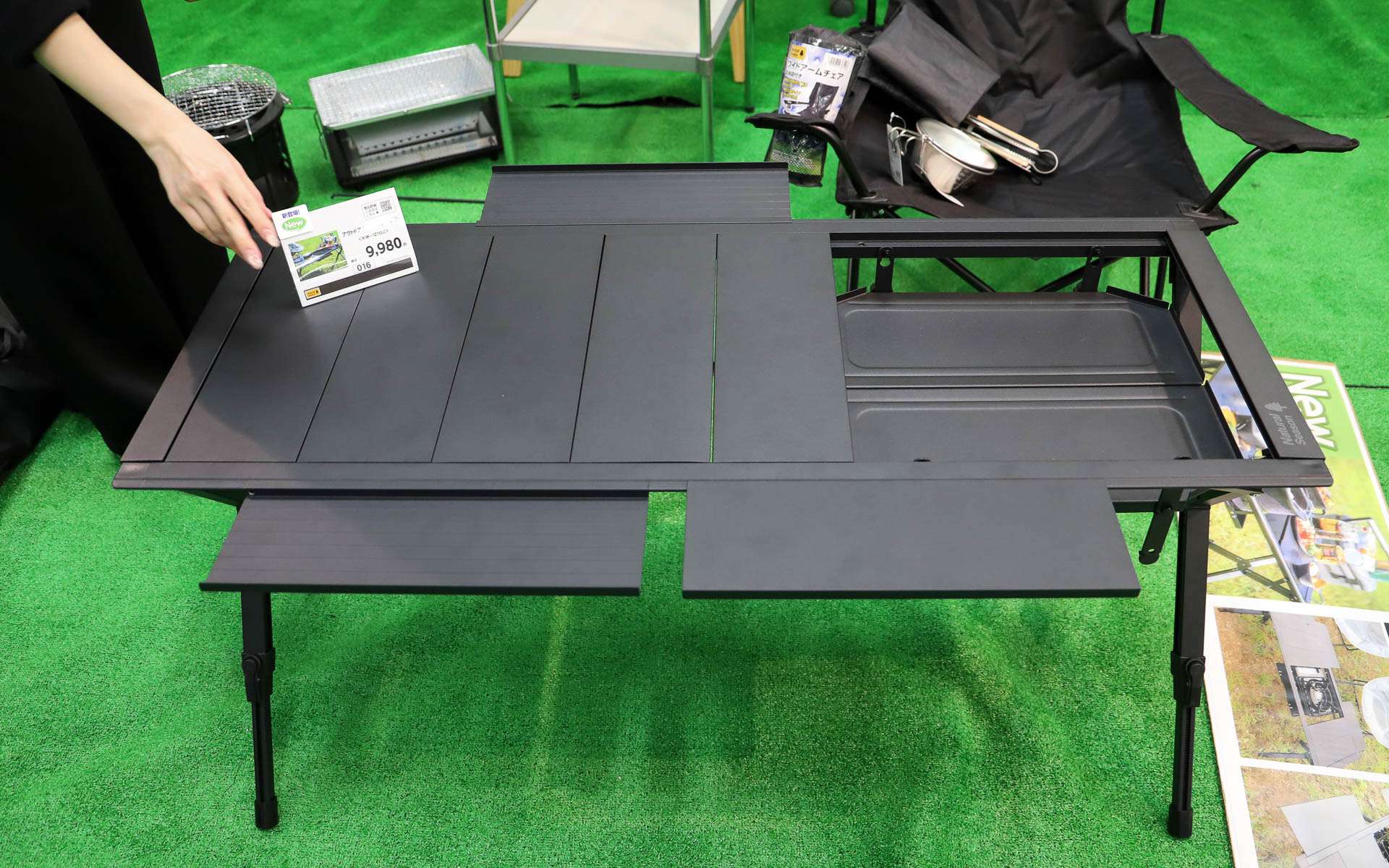 「アウトドアシステムテーブル」（9980円）。使うコンロや七輪のサイズに合わせてトレーの高さと位置が変更できるスグレモノ。天板は細かく取り外しでき、フレームに取り付けて拡張天板として利用可能。取り付けた天板は両面とも使えるので物が転がり落ちるのを防げる