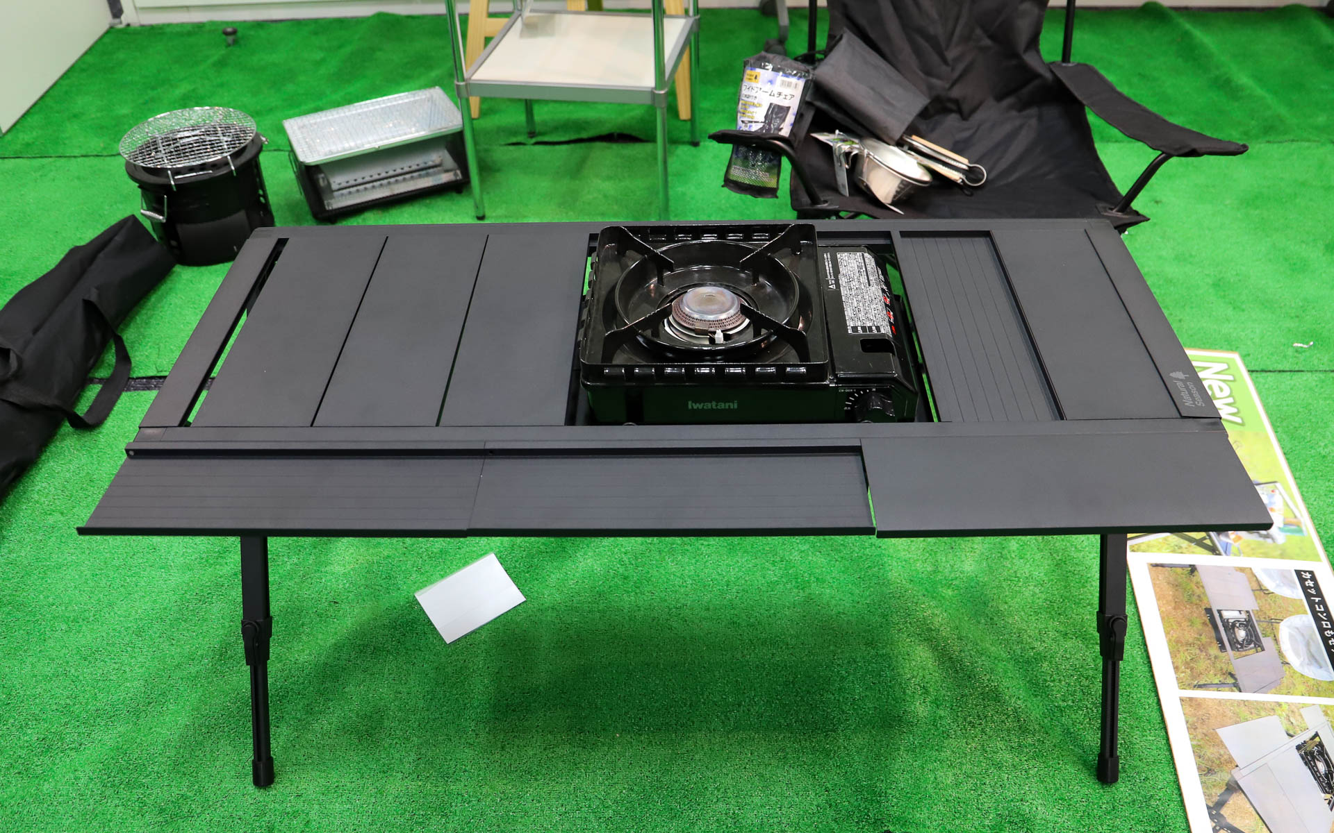 「アウトドアシステムテーブル」（9980円）。使うコンロや七輪のサイズに合わせてトレーの高さと位置が変更できるスグレモノ。天板は細かく取り外しでき、フレームに取り付けて拡張天板として利用可能。取り付けた天板は両面とも使えるので物が転がり落ちるのを防げる