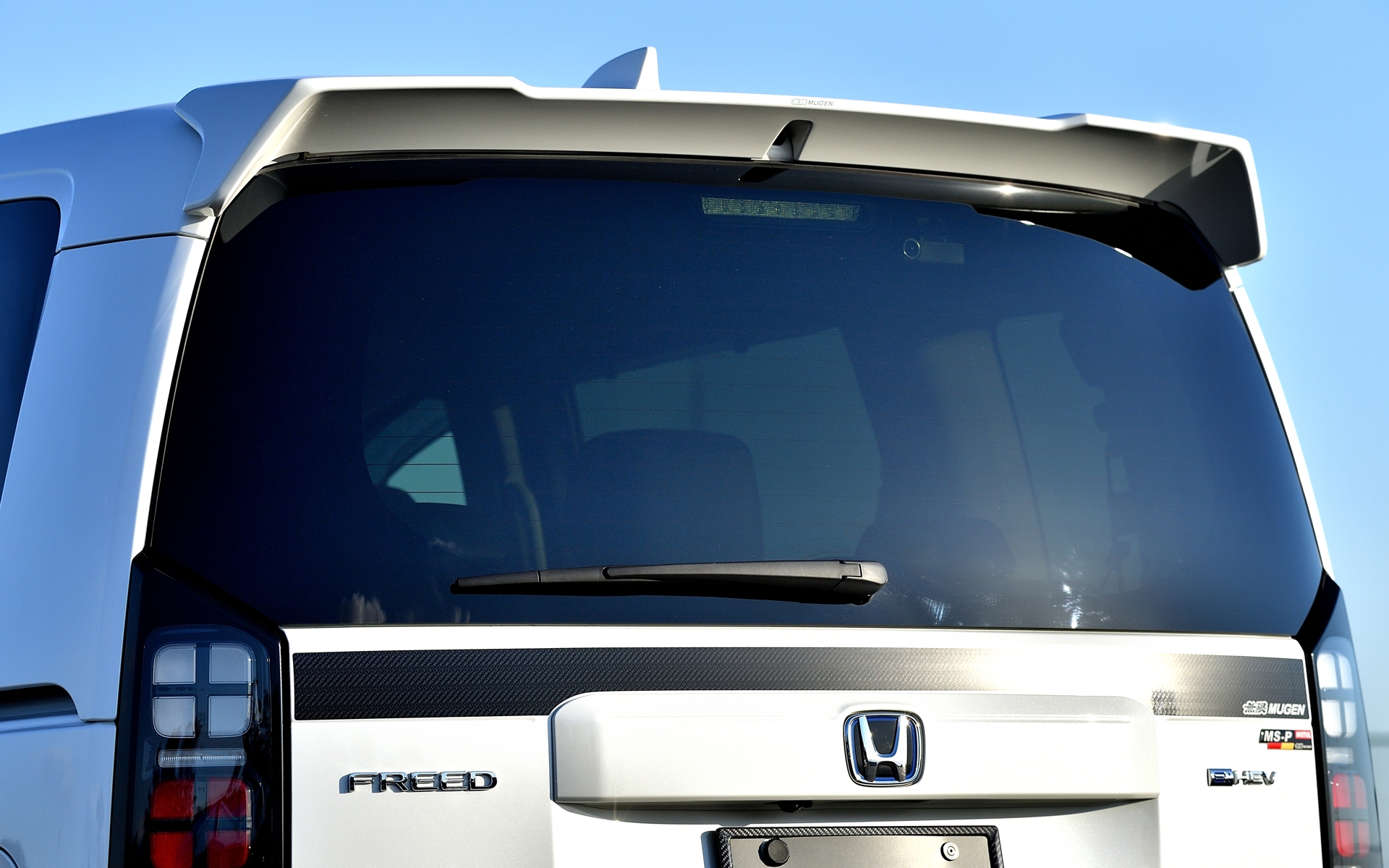 リアビューにボリューム感を持たせ、整流するようなデザインによりスポーティな印象を与える「テールゲートスポイラー」は12万1000円（未塗装品は11万円）。リアウインドウ下にアクセントを加えながら引き締める「テールゲートデカール」は1万5400円。（迷彩柄は1万7600円）