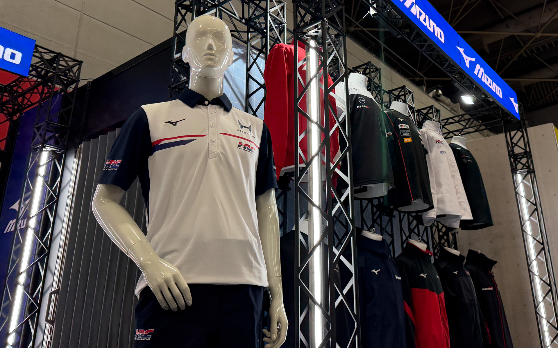 モータースポーツチームのユニフォームを展示。写真手前はHRCとミズノによるIndycar/SF/ SGT/IMSA用の2026年新ユニフォーム