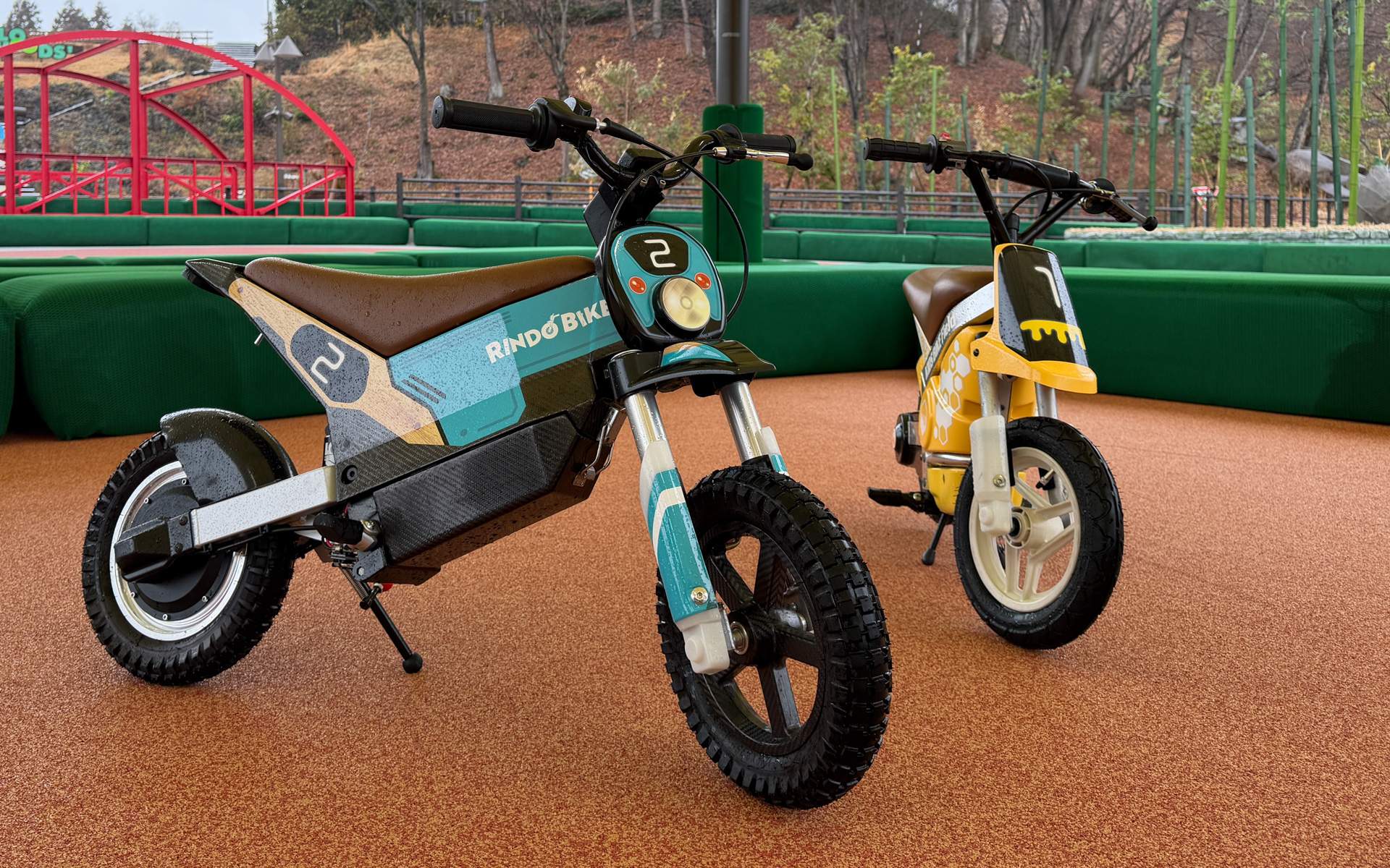 「オフロードツーリング リンドーバイク」のバイク（写真左）。デザインはオフロードらしさを表現する木目調を採用し、カラーには林道の緑が多い中でも映える、やわらかい印象のあるくすみオレンジを採用した