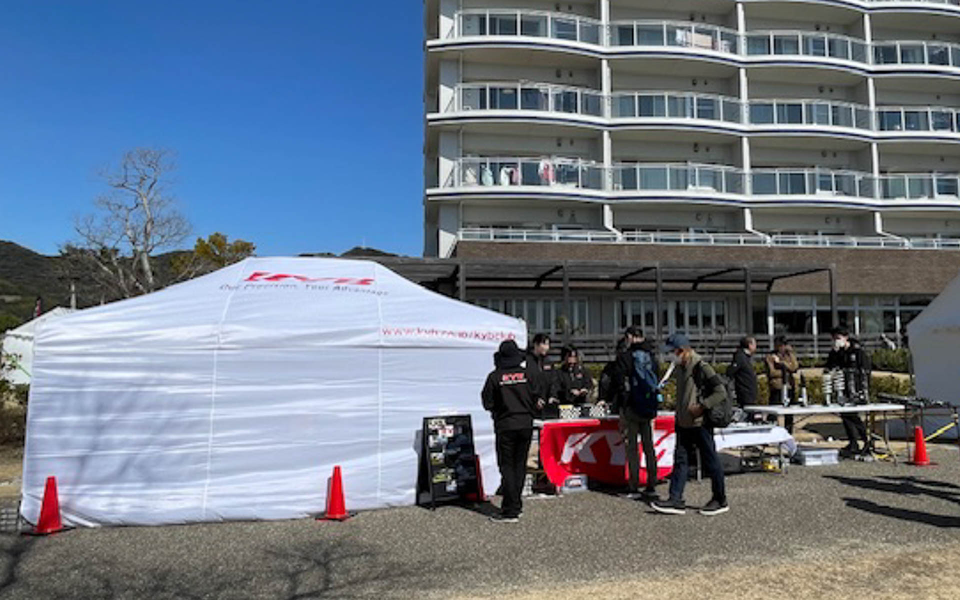 土曜日のブース。朝から1張りのテントをたたんだので露天で皆、日に焼けた。女子が多いのに……。この後左のテントもたたむことになるとは