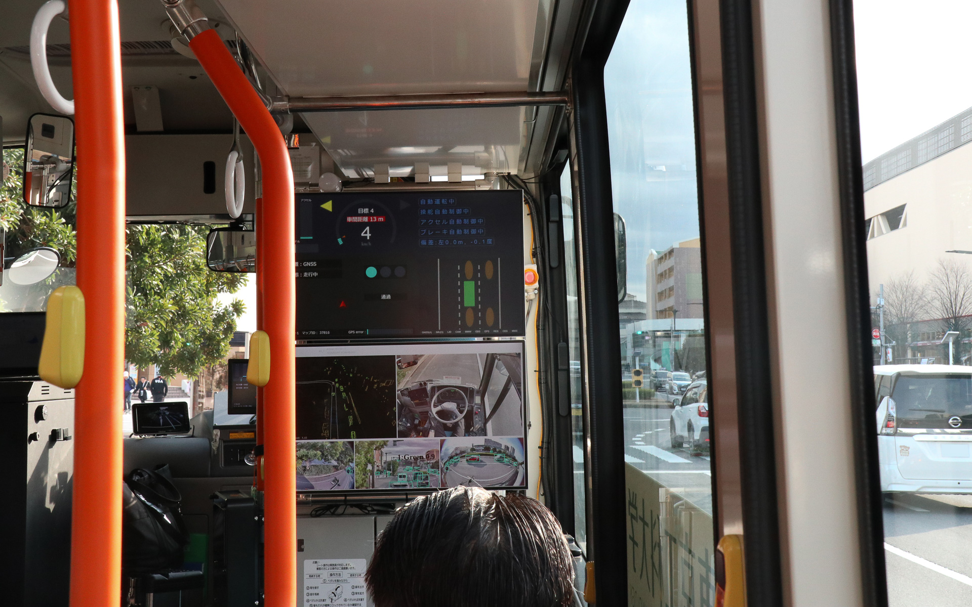 自動運転中の車内。運転席後方のディスプレイに自動運転に関連する情報がリアルタイム表示されている