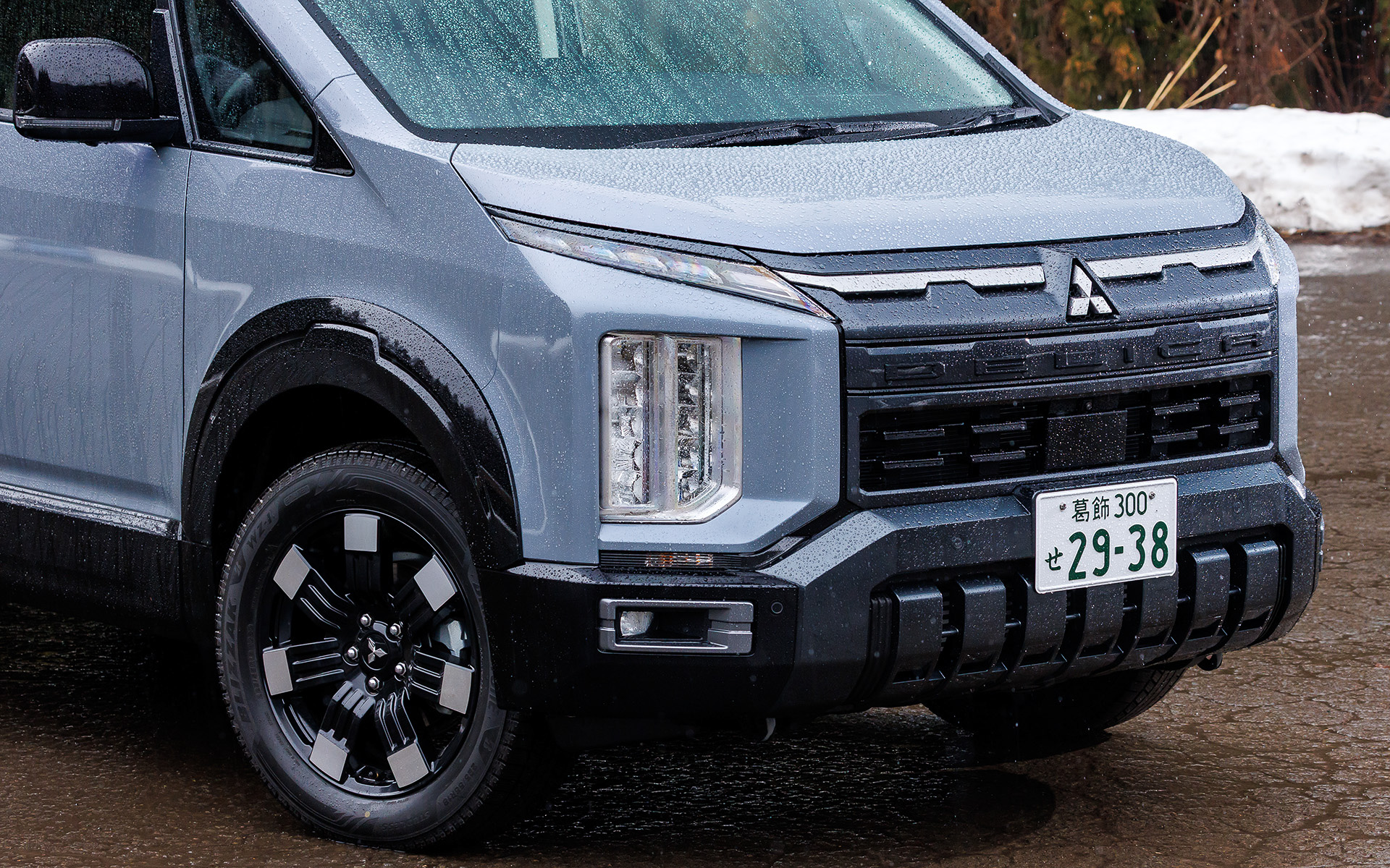 エクステリアではフロントグリルとフロントバンパーをシンプルで立体感のある力強いデザインにするとともに、リアは左右につながっていたテールランプから中央に「DELICA」ロゴを配置するスタイルに変更。また、ボディサイドにはワイドで安定感のある足まわりと高い走破性を想起させるホイールアーチモールを新採用し、力強さとギア感を高めた。加えて新デザインの18インチアルミホイールも採用する