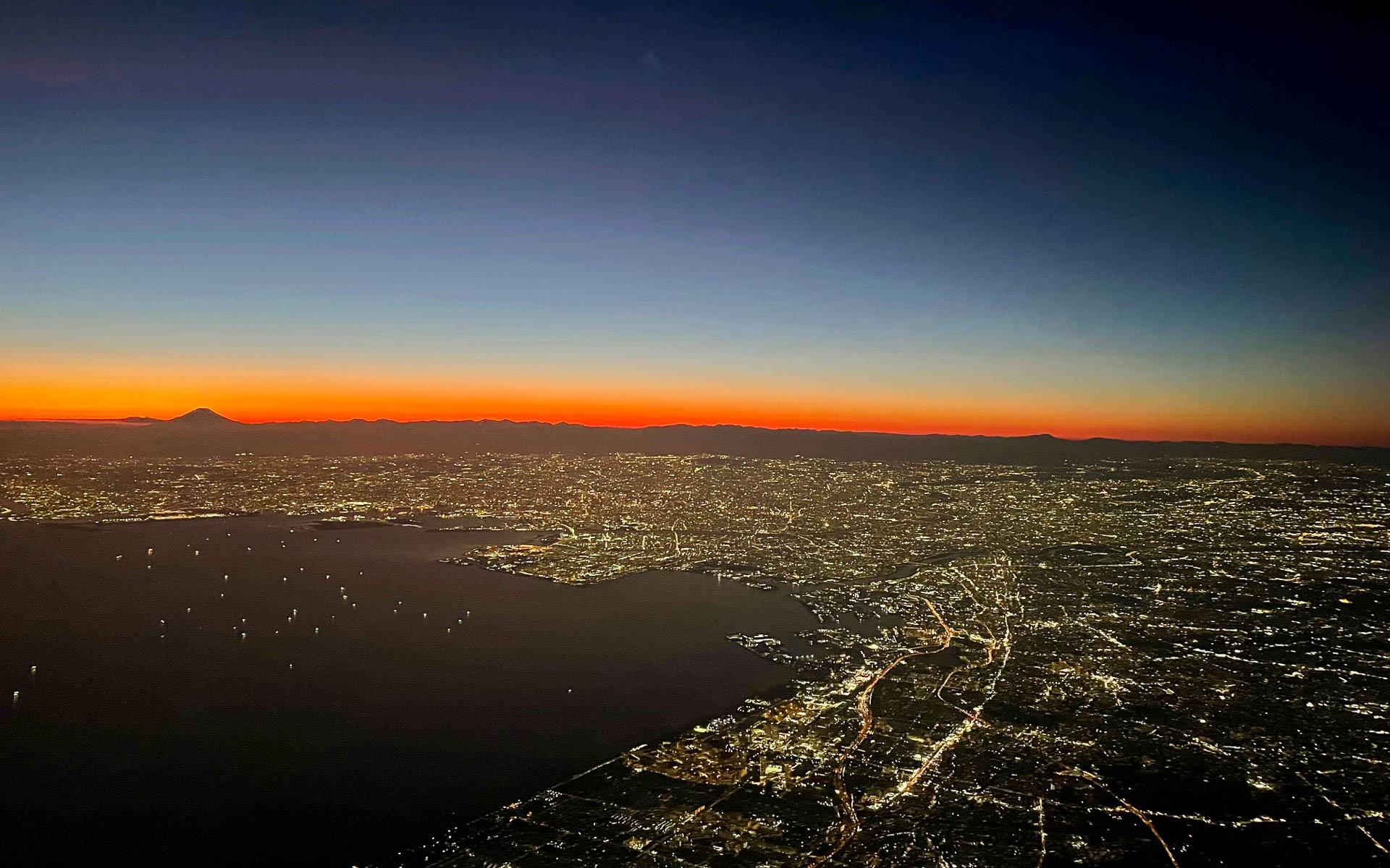 日が沈む寸前の東京。震災後しばらくは銀をまき散らしたような夜景は、暗転したように真っ暗になった。富士山はいつも孤高の存在だ