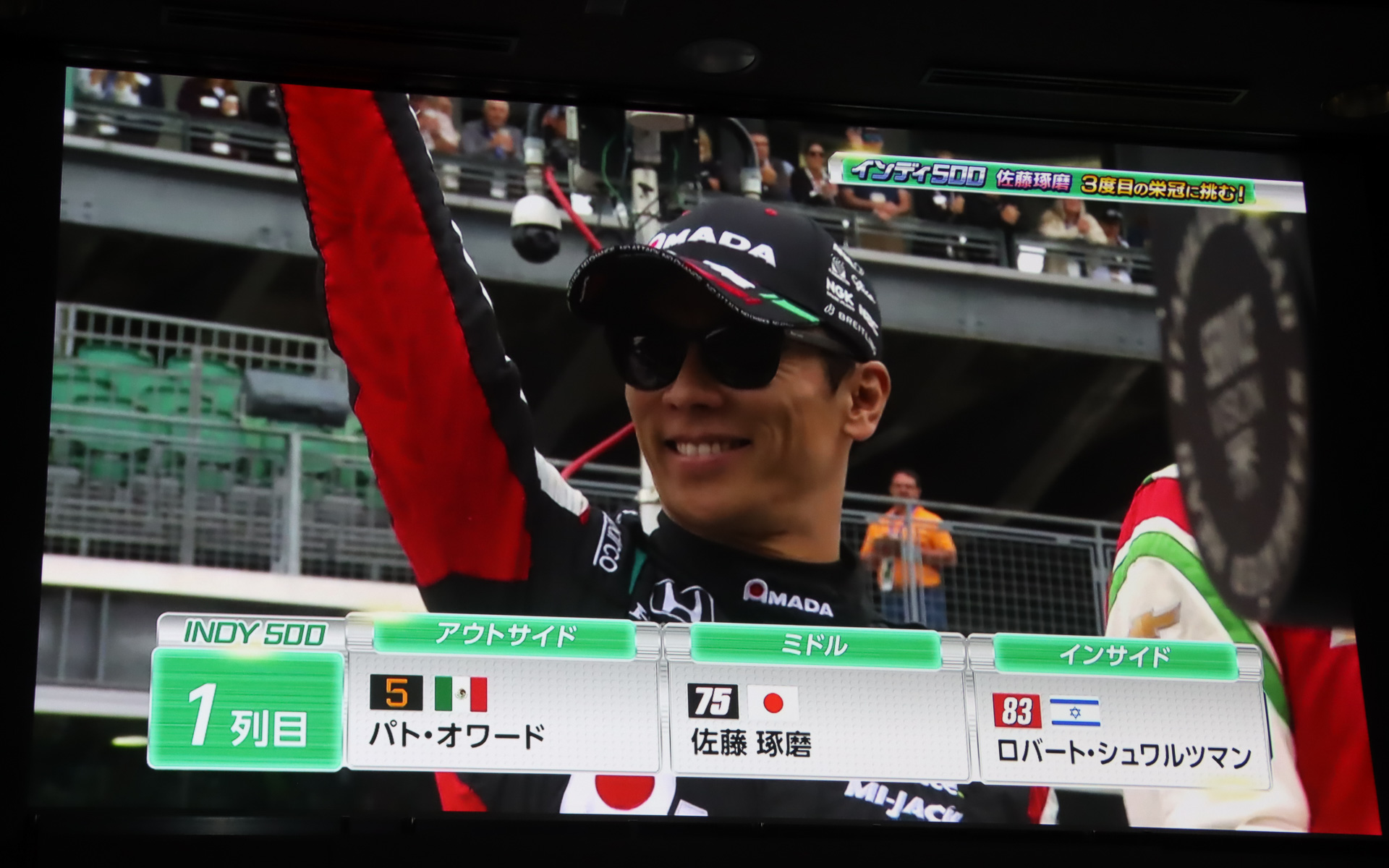 ステージ上のスクリーンで上映されたインディ500 2025年大会のダイジェスト。予選2番手からのスタートで51周をトップ走行したが、一斉にピットインしたタイミングで佐藤琢磨選手は自分のピットスペースで停止できず、大きく順位を落として9位フィッシュとなった