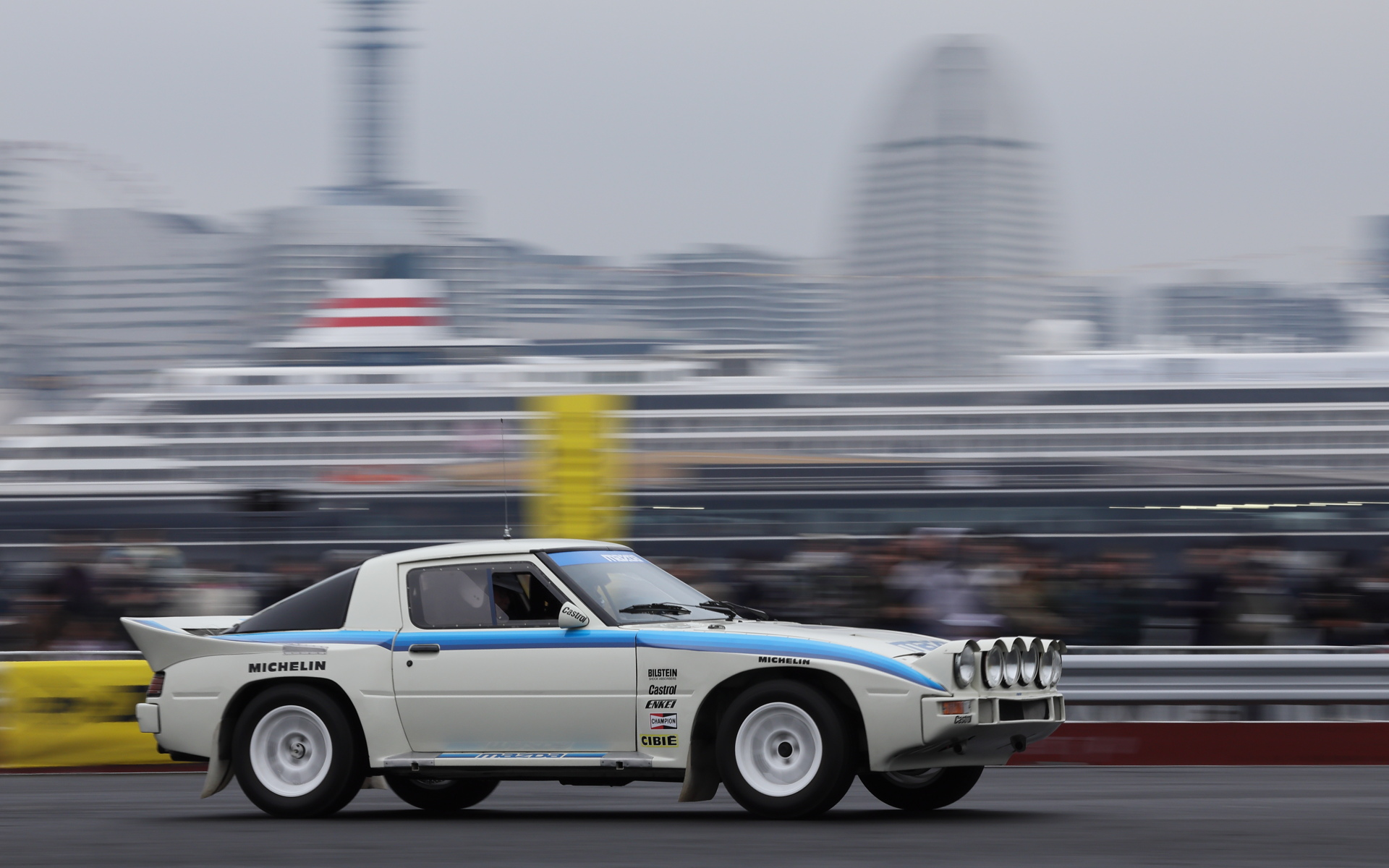 ヨコハマグランドインターコンチネンタルホテルや客船飛鳥IIをバックに走るSA22型RX-7のグループBマシン