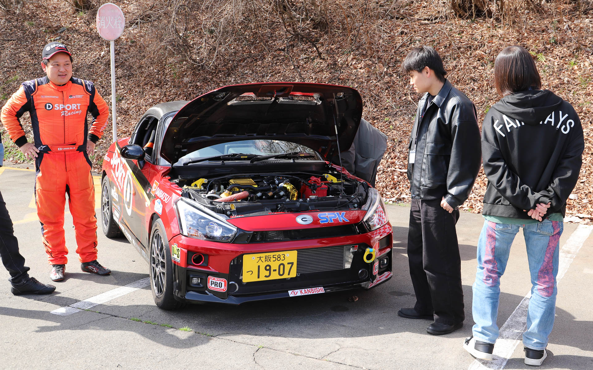 学生たちは展示されたレース車両を興味津々に見ており、相原氏やスタッフが車両の説明を行なう姿が見られた