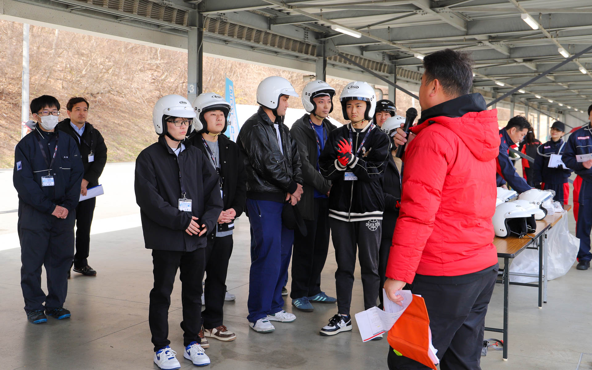 軽商用EVの「e-ハイゼット カーゴ」でショートコースを走行するために、緊張した面持ちで準備を進める学生たち。普段クルマに乗らない学生や、初めてサーキットを走る学生も参加しているため、電源ONの仕方、走り出すにはシフトをドライブに入れること、走り終えてピットに戻ってきたらシフトをパーキングに入れることなど、細かな説明をしっかりと聞いていた