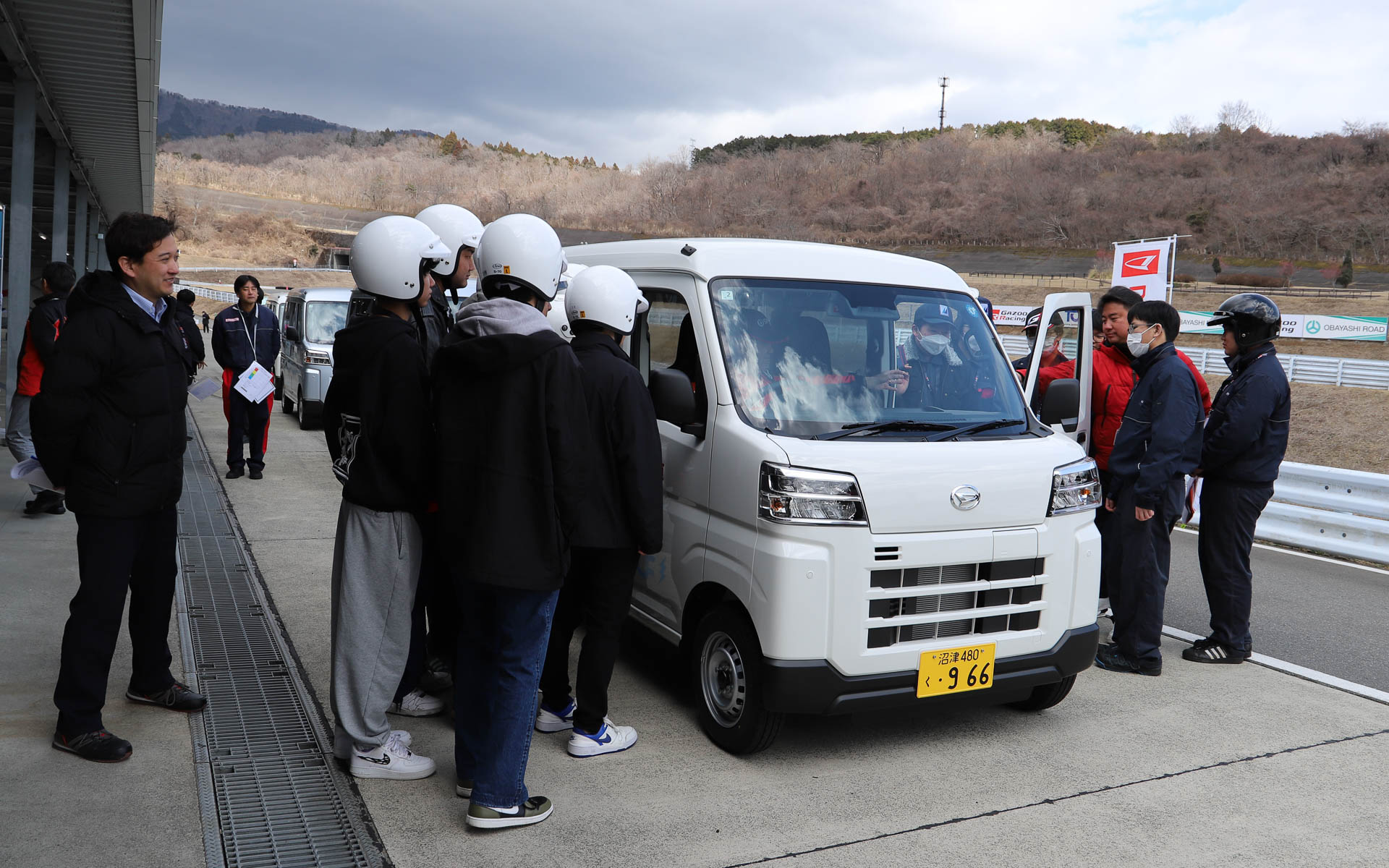 軽商用EVの「e-ハイゼット カーゴ」でショートコースを走行するために、緊張した面持ちで準備を進める学生たち。普段クルマに乗らない学生や、初めてサーキットを走る学生も参加しているため、電源ONの仕方、走り出すにはシフトをドライブに入れること、走り終えてピットに戻ってきたらシフトをパーキングに入れることなど、細かな説明をしっかりと聞いていた