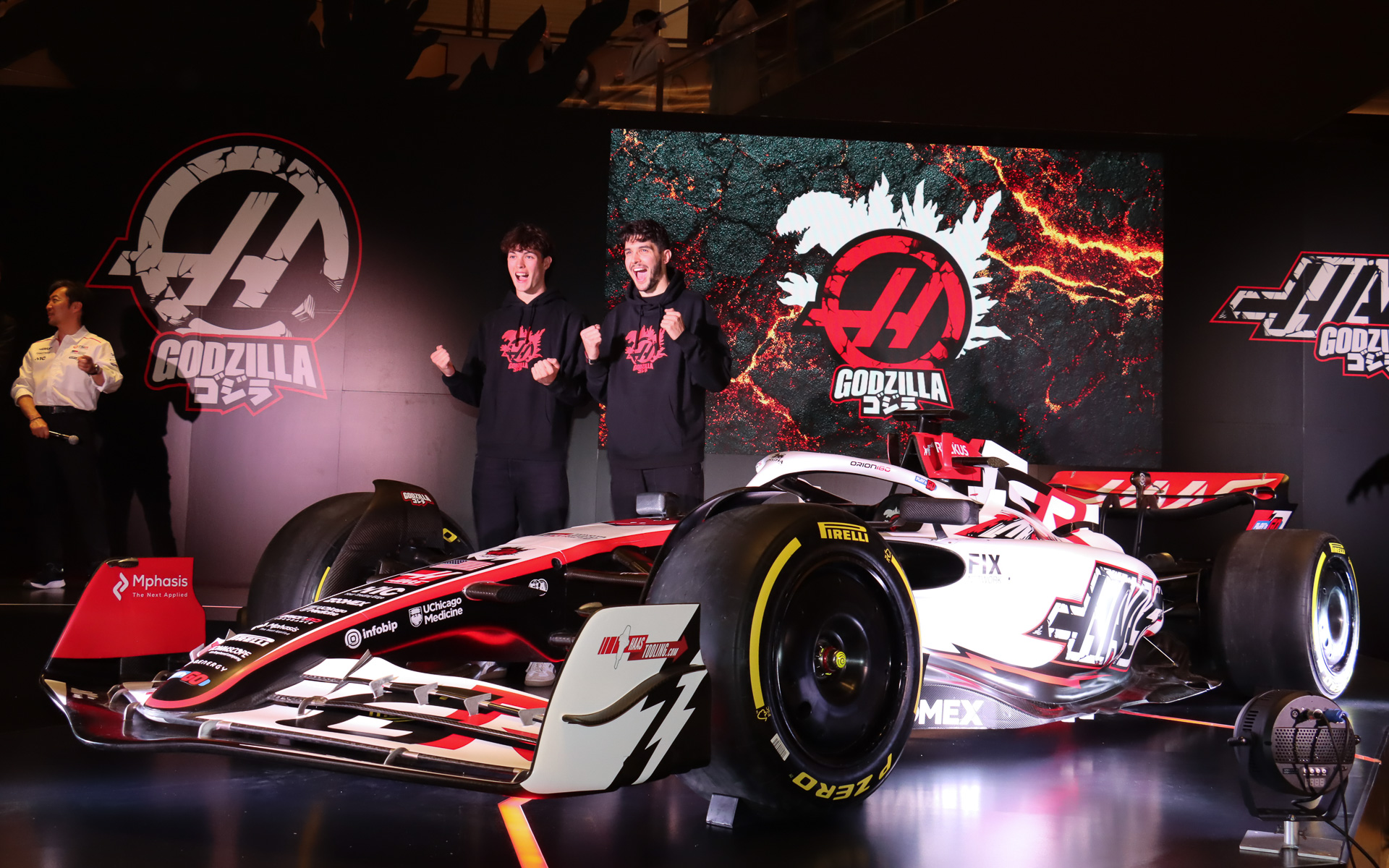 「ゴジラリバリー」を施された「VF-26」をアンベールしたあと、マシンの横でゴジラを連想させるポーズを披露したオリバー・ベアマン選手（左）とエステバン・オコン選手（右）