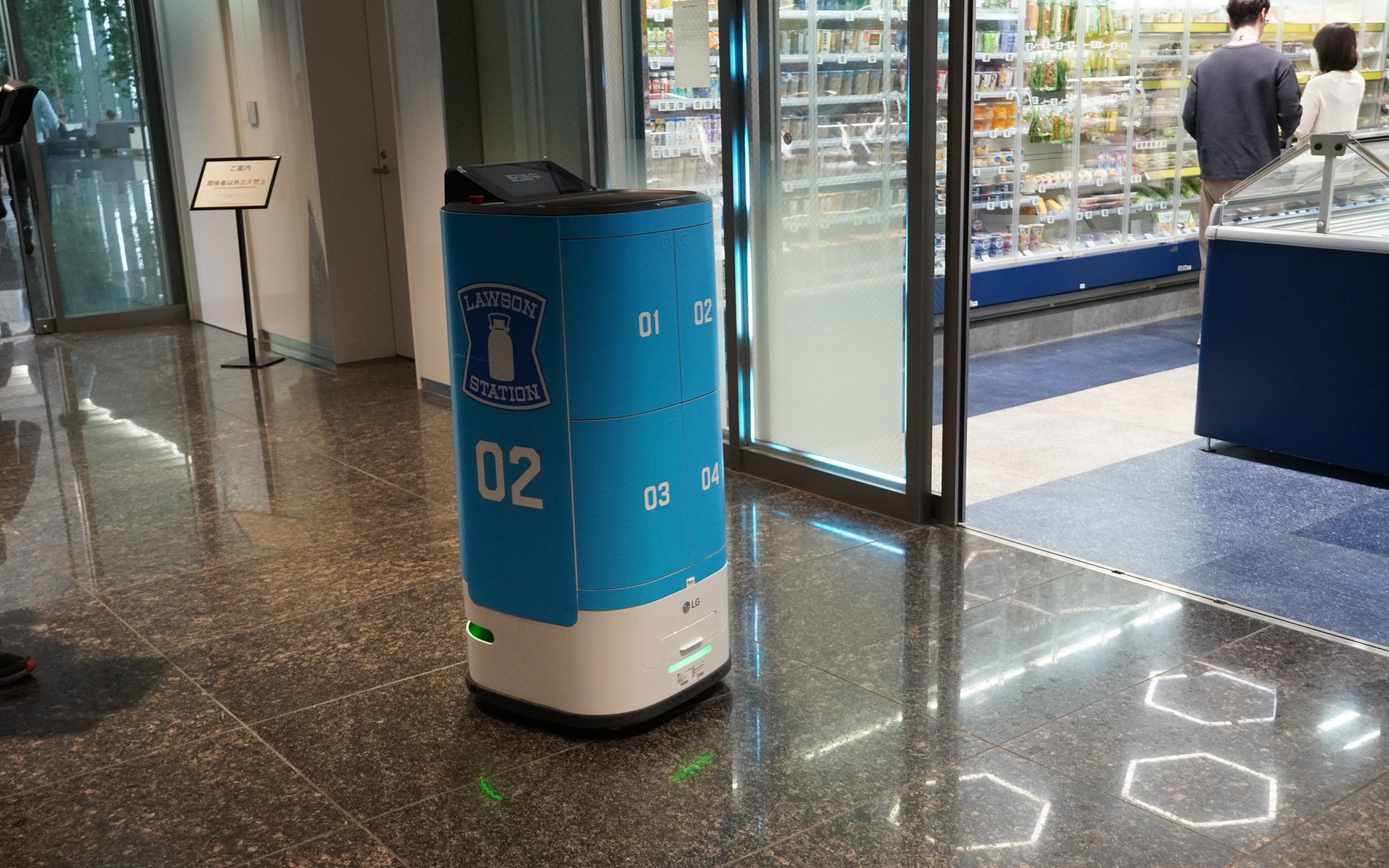 TAKANAWA GATEWAY CITYにあるKDDIのオフィスにはローソンの自動配達がある。注文するとローソンで商品を積み込み、セキュリティゲートを通過し、エレベーターに乗って注文者の席まで届けてくれる