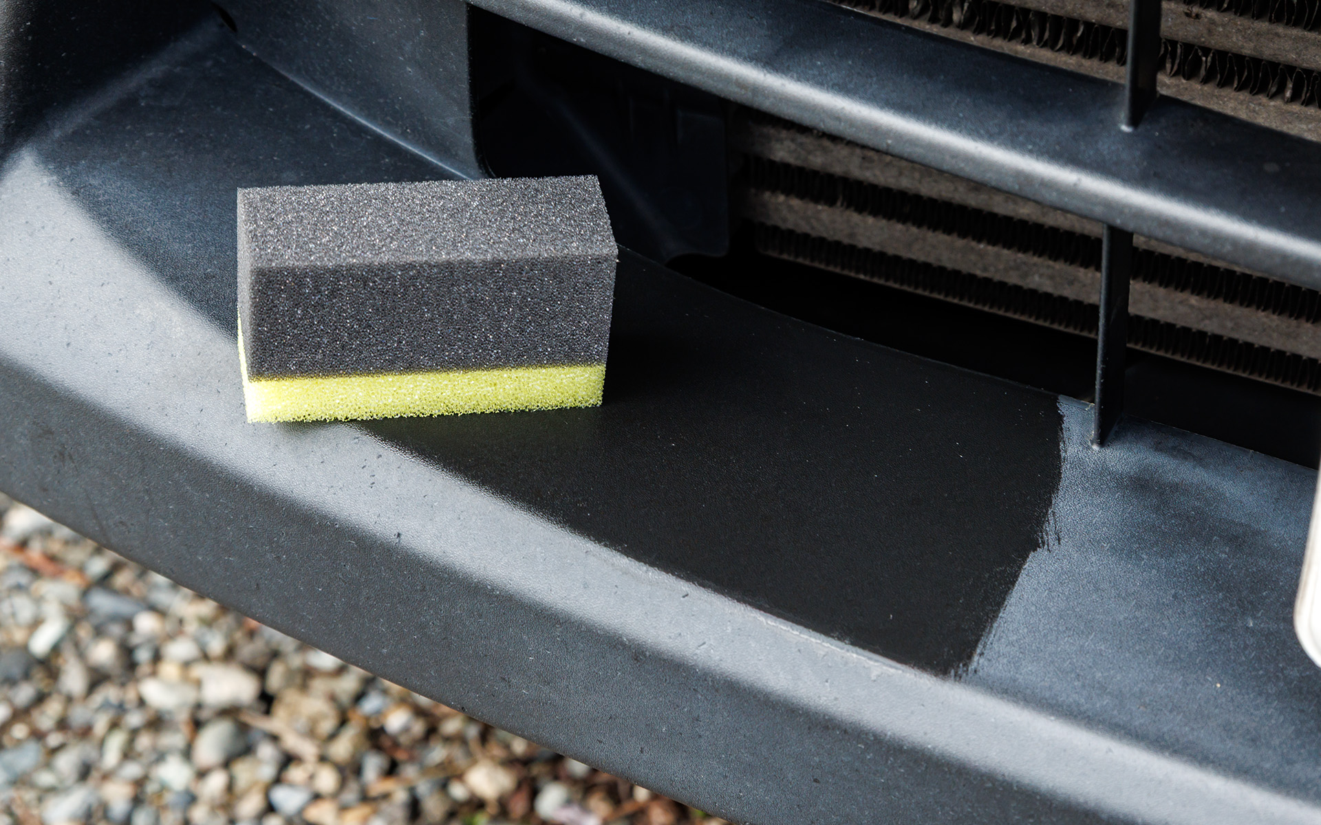 スポンジにコーティング剤を含ませフロントバンパーを塗ってみる。ひと拭きで黒さ復活！　凄い