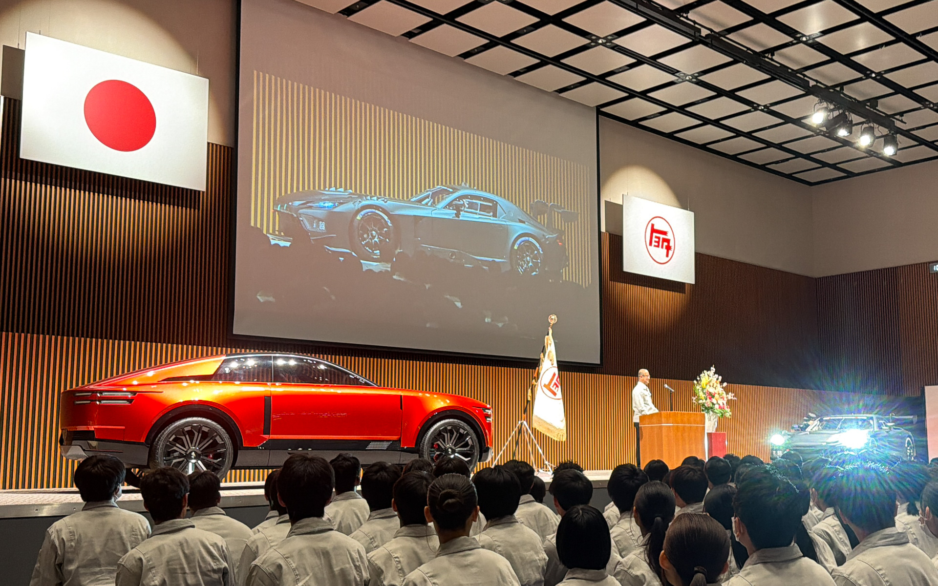 トヨタ自動車株式会社 事務本館で開催された2026年度入社式。4月1日から新たに社長に就任した近健太氏のもとで行なわれ、壇上には豊田式木製人力織機、センチュリークーペ、GR GT3を配置。中嶋裕樹副社長がGR GT3のV8サウンドで歓迎した