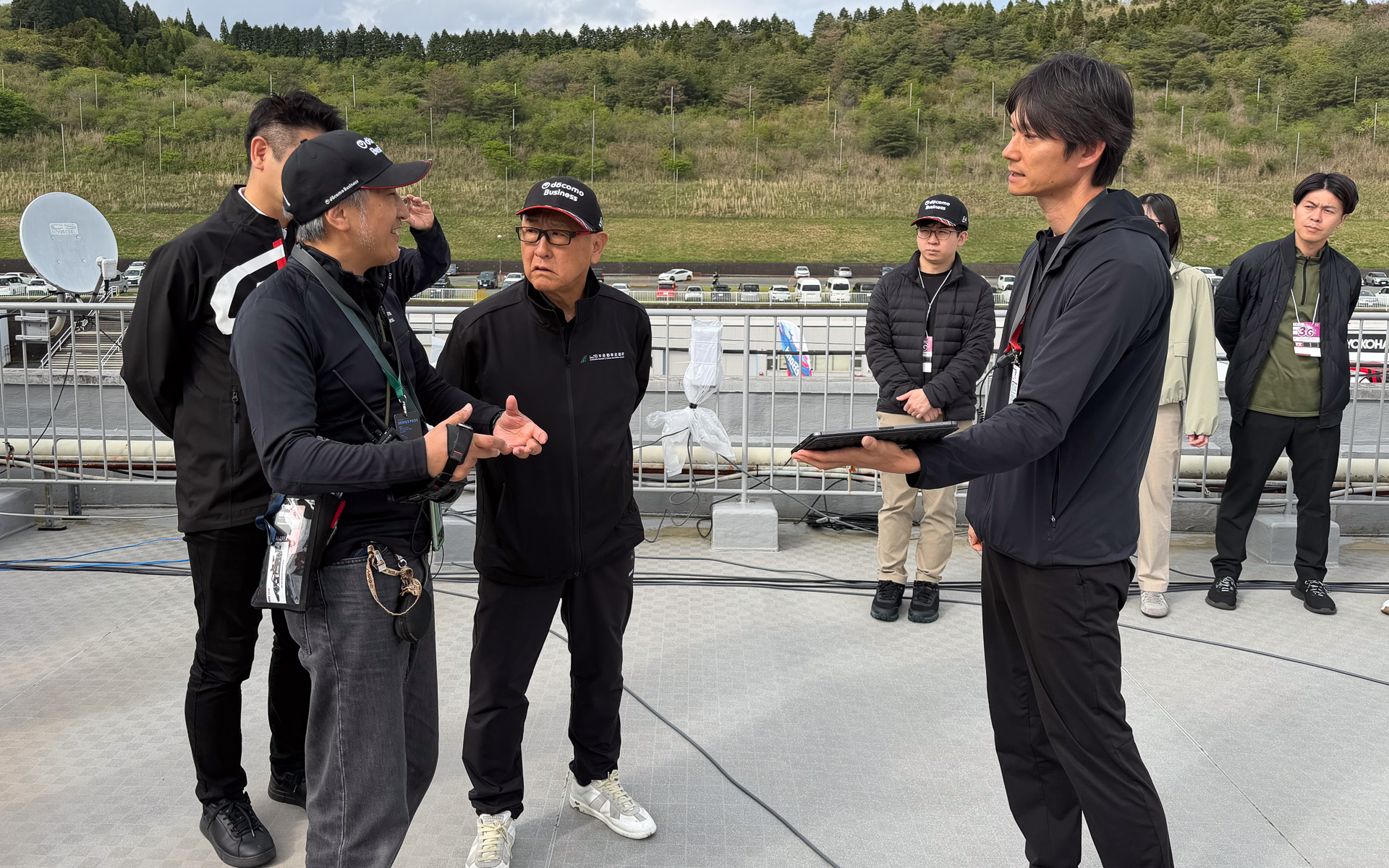 NTTドコモビジネス株式会社 イノベーションセンター テクノロジー部門 担当課長 里和勇人氏（左）から説明を受ける豊田章男会長