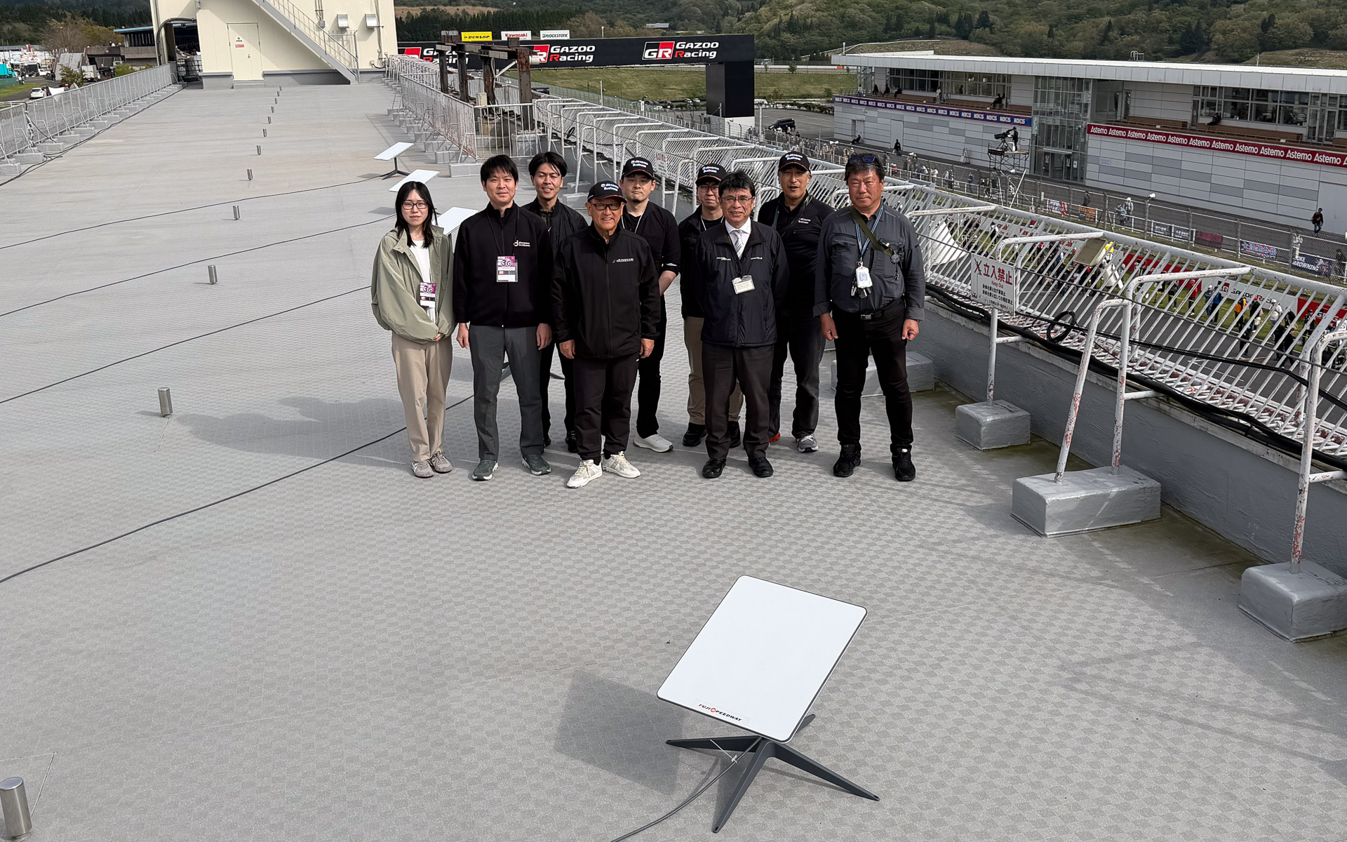 パドックビル屋上のスターリンクを視察後、関係者とともに記念写真