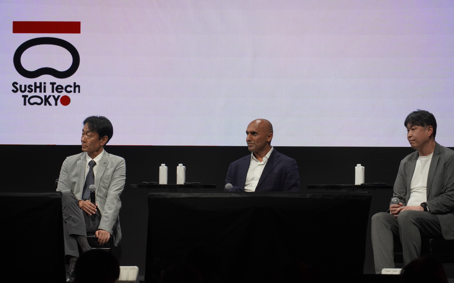 SusHi Tech Tokyo 2026で登壇した、いすゞ自動車株式会社 常務執行役員 SVP渉外担当役員 開発部門SVP 佐藤浩至氏（左）、Applied Intuition, Inc. 共同創設者兼 CEO カサール・ユニス氏（中央）、日産自動車株式会社 杉本一馬氏（右）